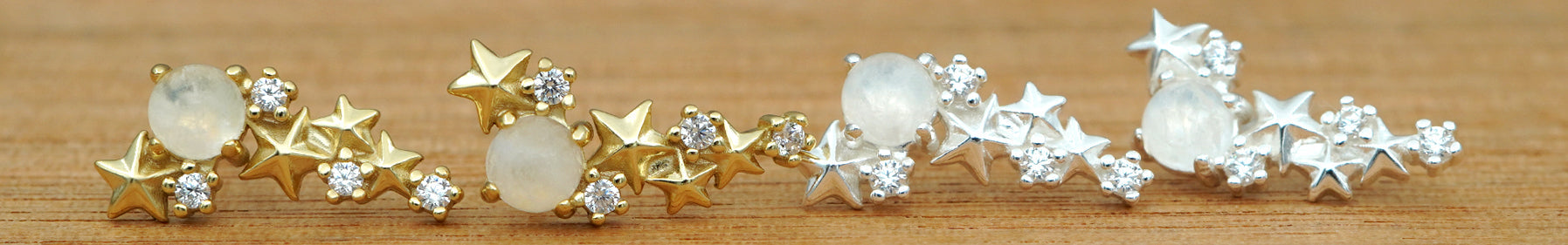 Matariki Earrings on a wooden background in gold and silver