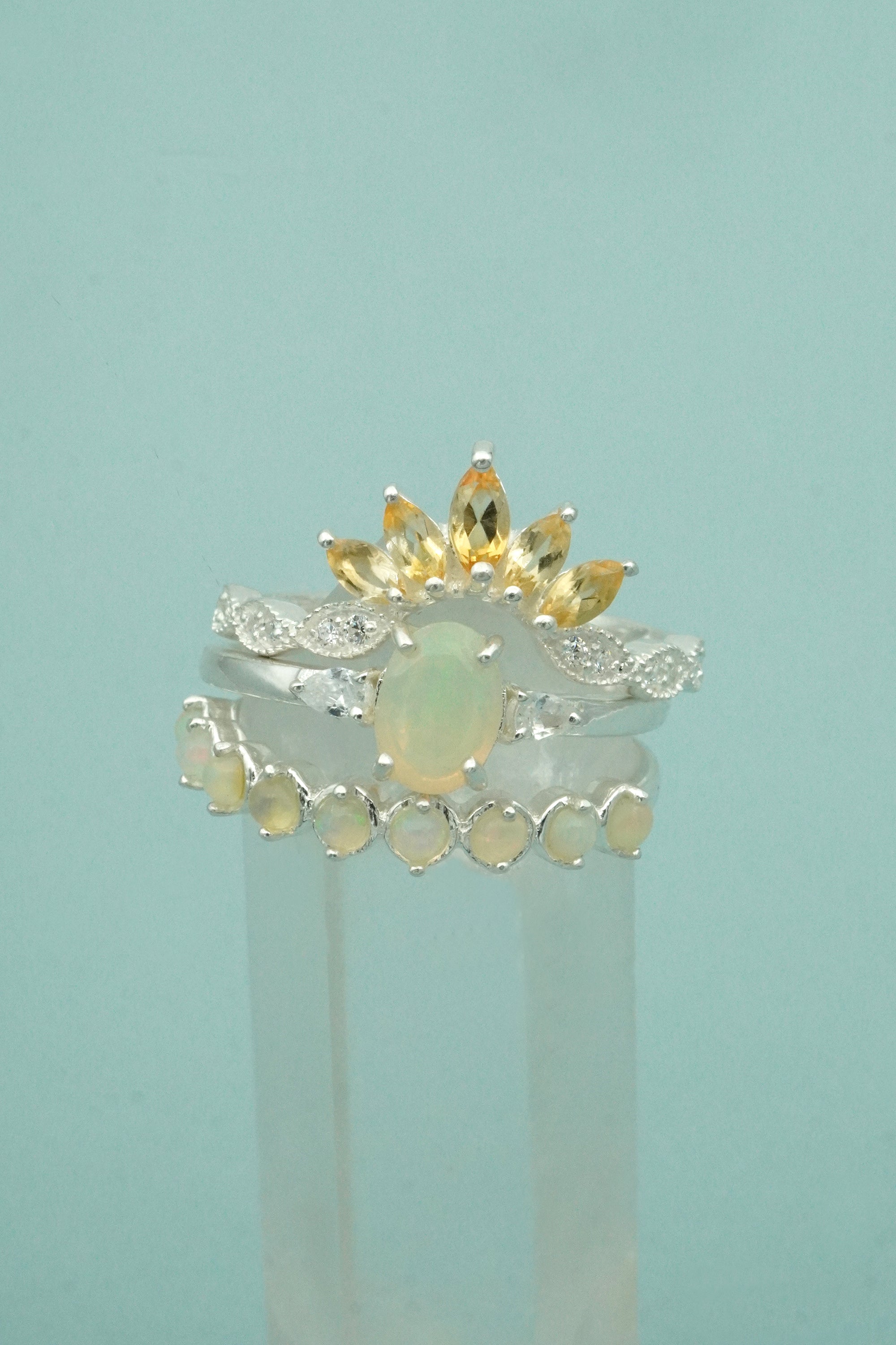 Three silver stacking rings with different designs on a light blue background