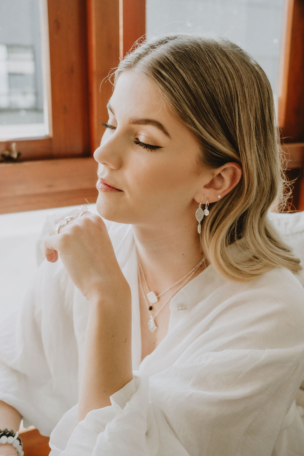 Woman wearing a white outfit with jewelry indoors