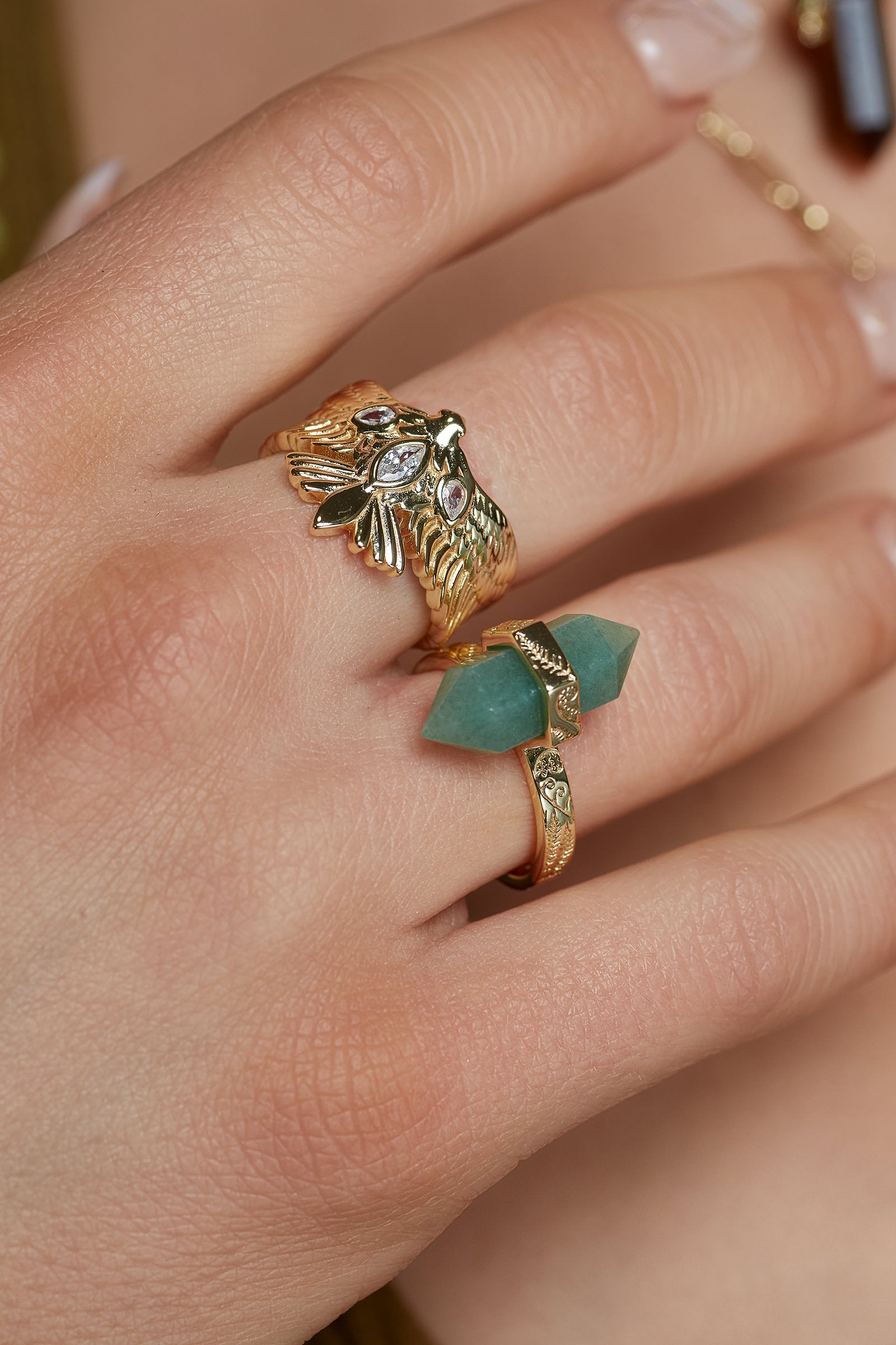 Gold Bird ring featuring a hawk with outstretched wings and a green aventurine crystal ring on a hand.