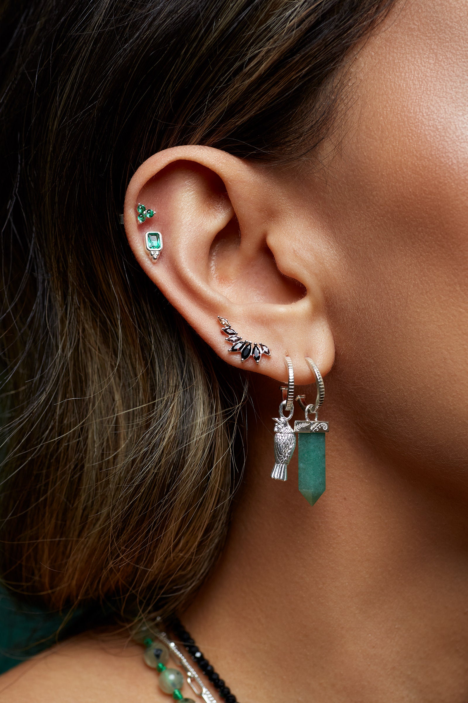 Close-up of an ear with multiple silver stacked stud earrings on a blurred background