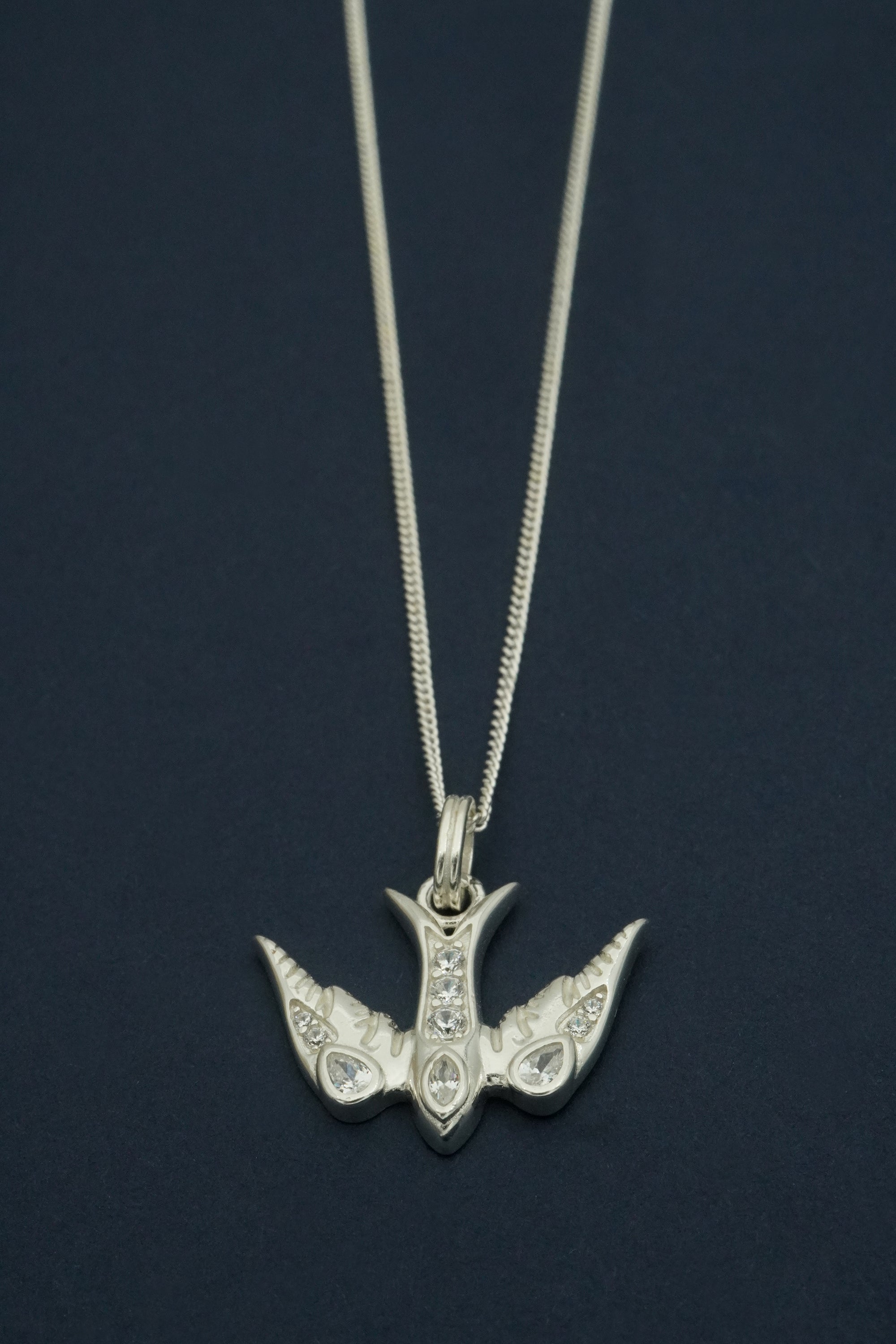 Silver pendant bird necklace on a dark background