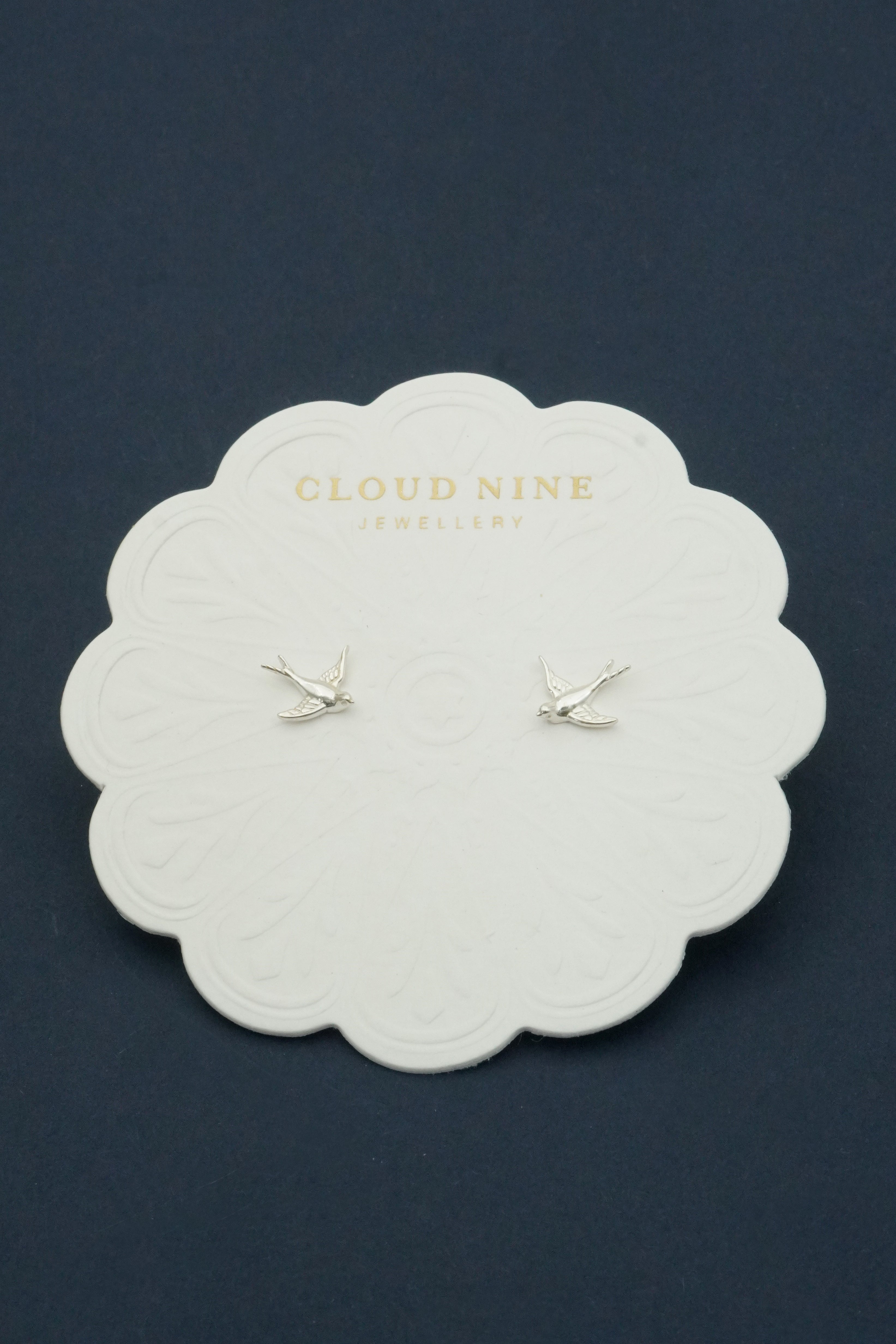 Pair of silver bird-shaped earrings on a 'Cloud Nine Jewellery' branded card against a dark background