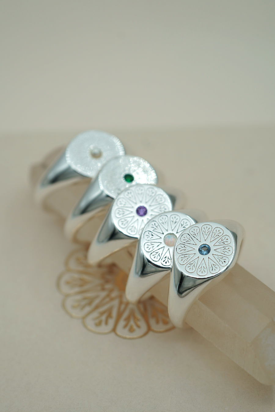 Silver May Emerald Signet Birthstone Rings stacked on crystals