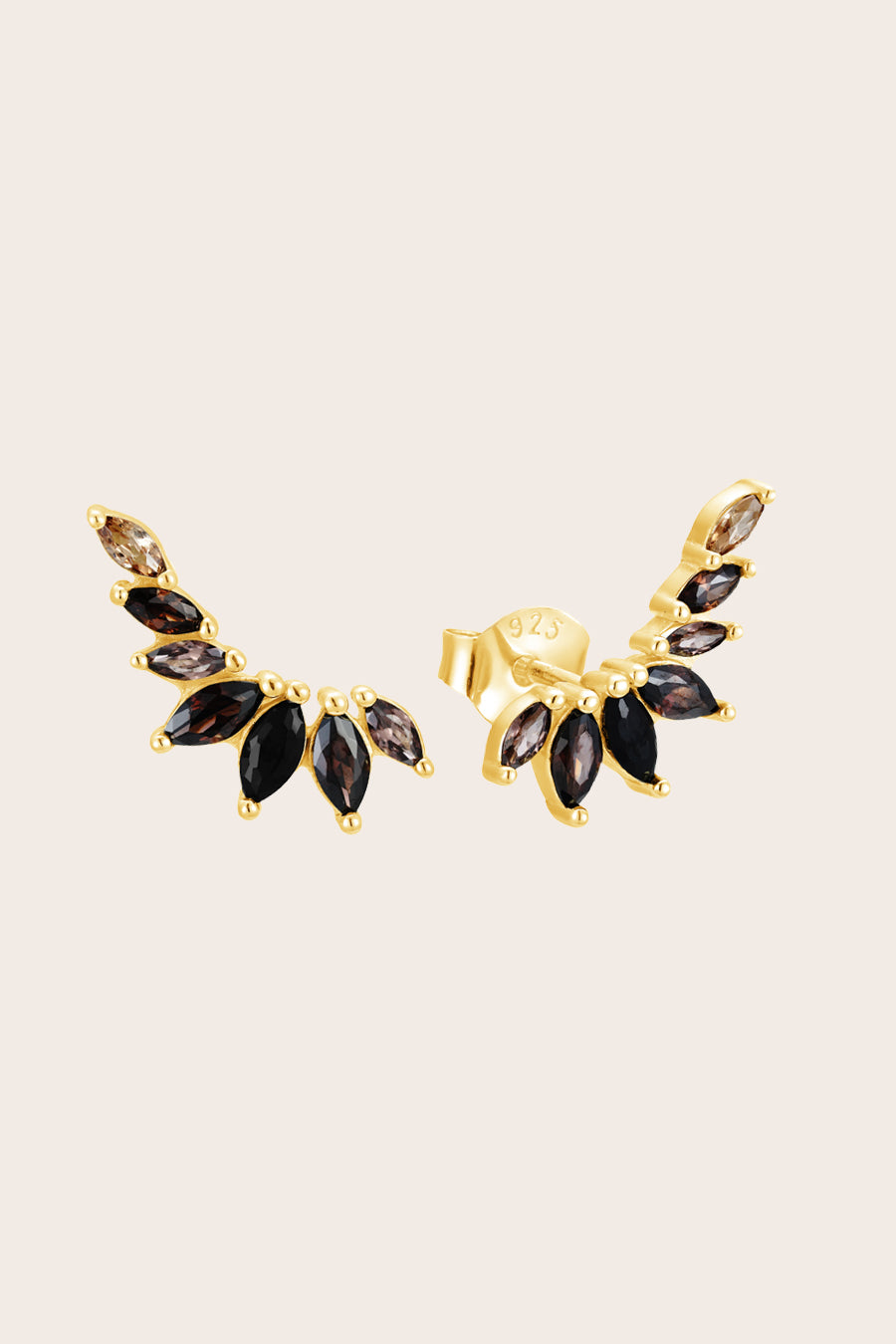 Gold climber earrings with black and brown gemstones on a beige background