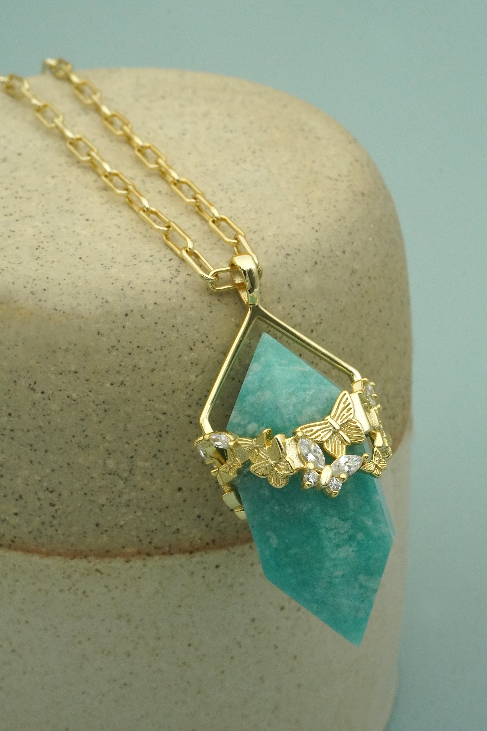 Butterfly Necklace with turquoise pendant and gold chain on beige stand