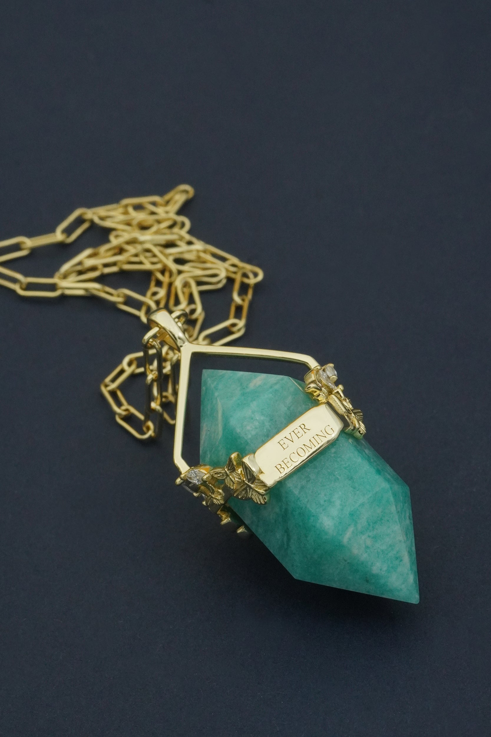 Turquoise crystal pendant necklace with gold chain on a dark background