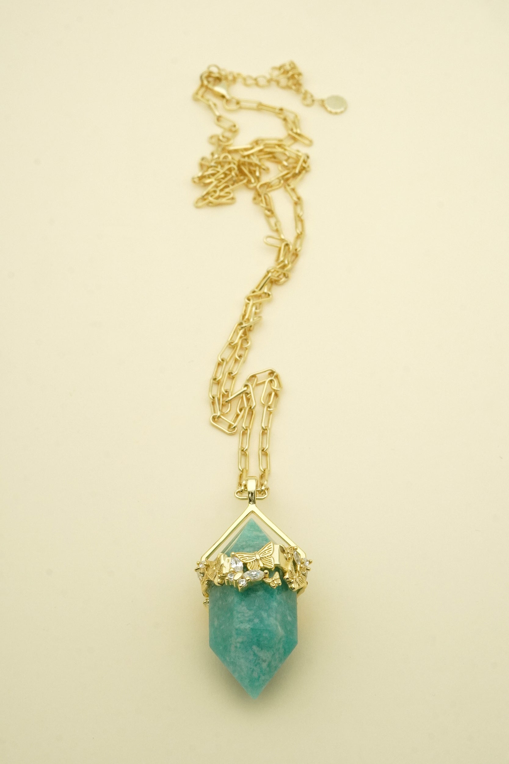 Gold necklace with a turquoise pendant on a beige background