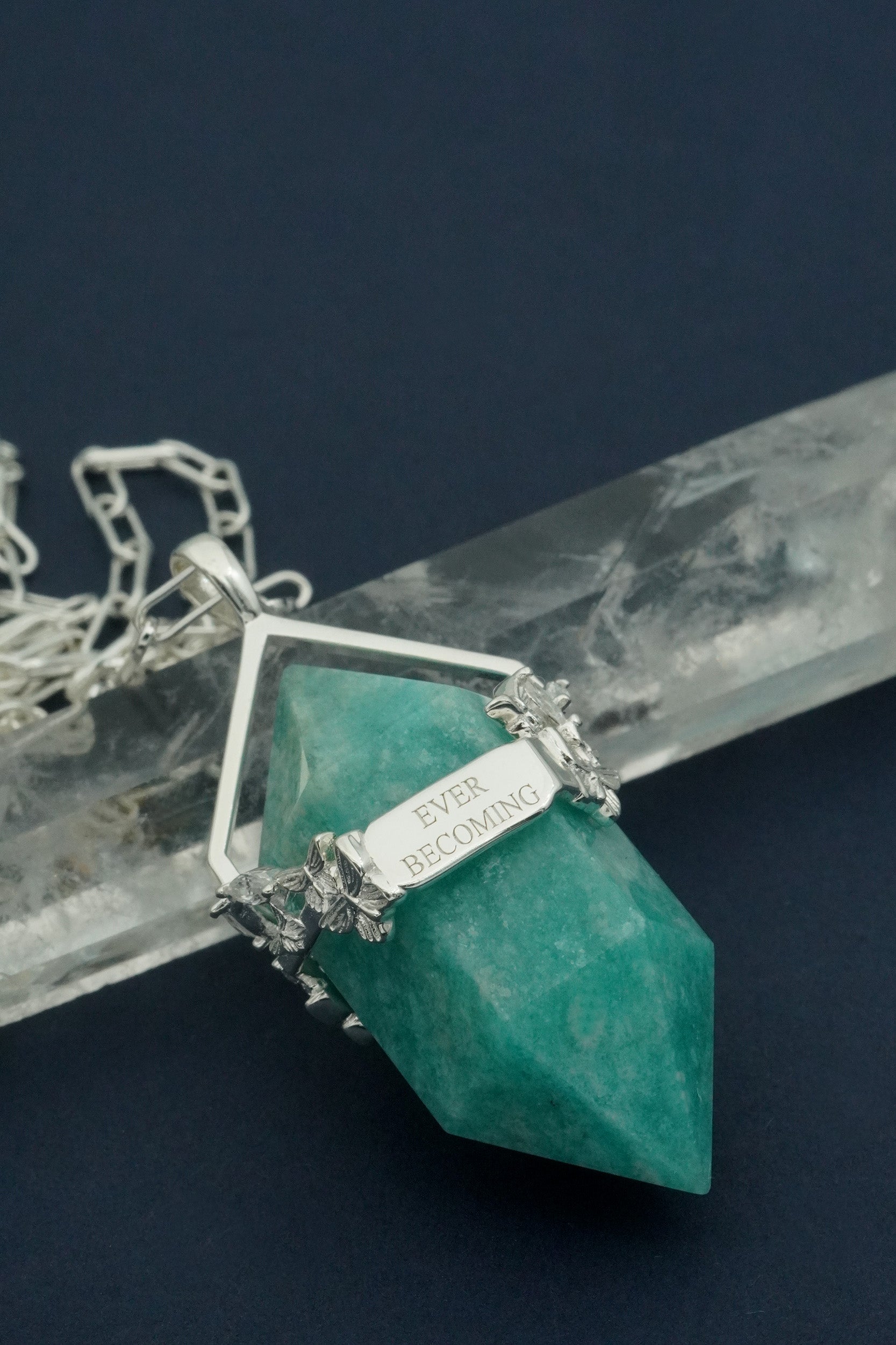 Turquoise crystal pendant with silver chain on a dark background