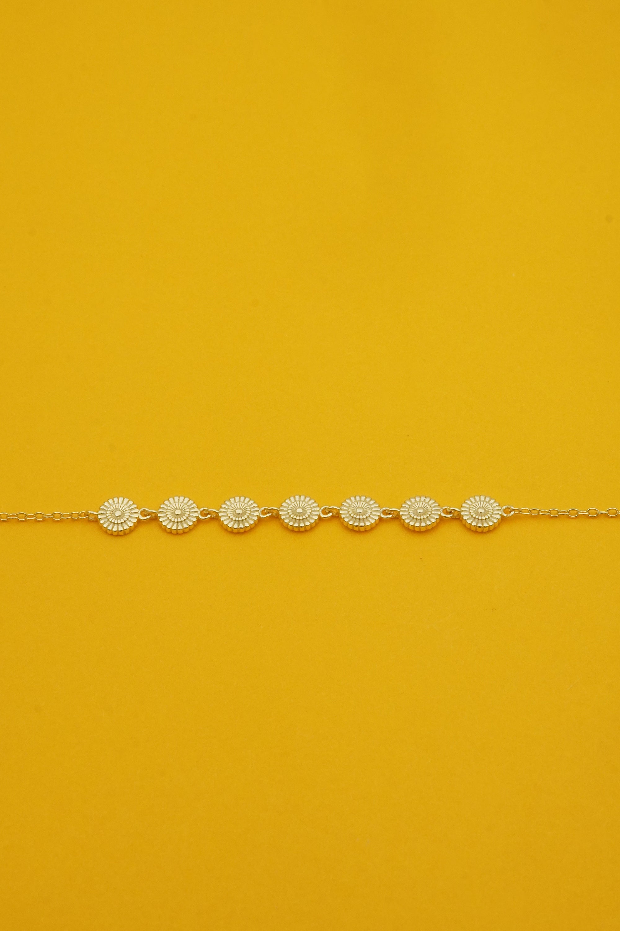 Delicate bracelet with circular flowers patterns on a mustard yellow background