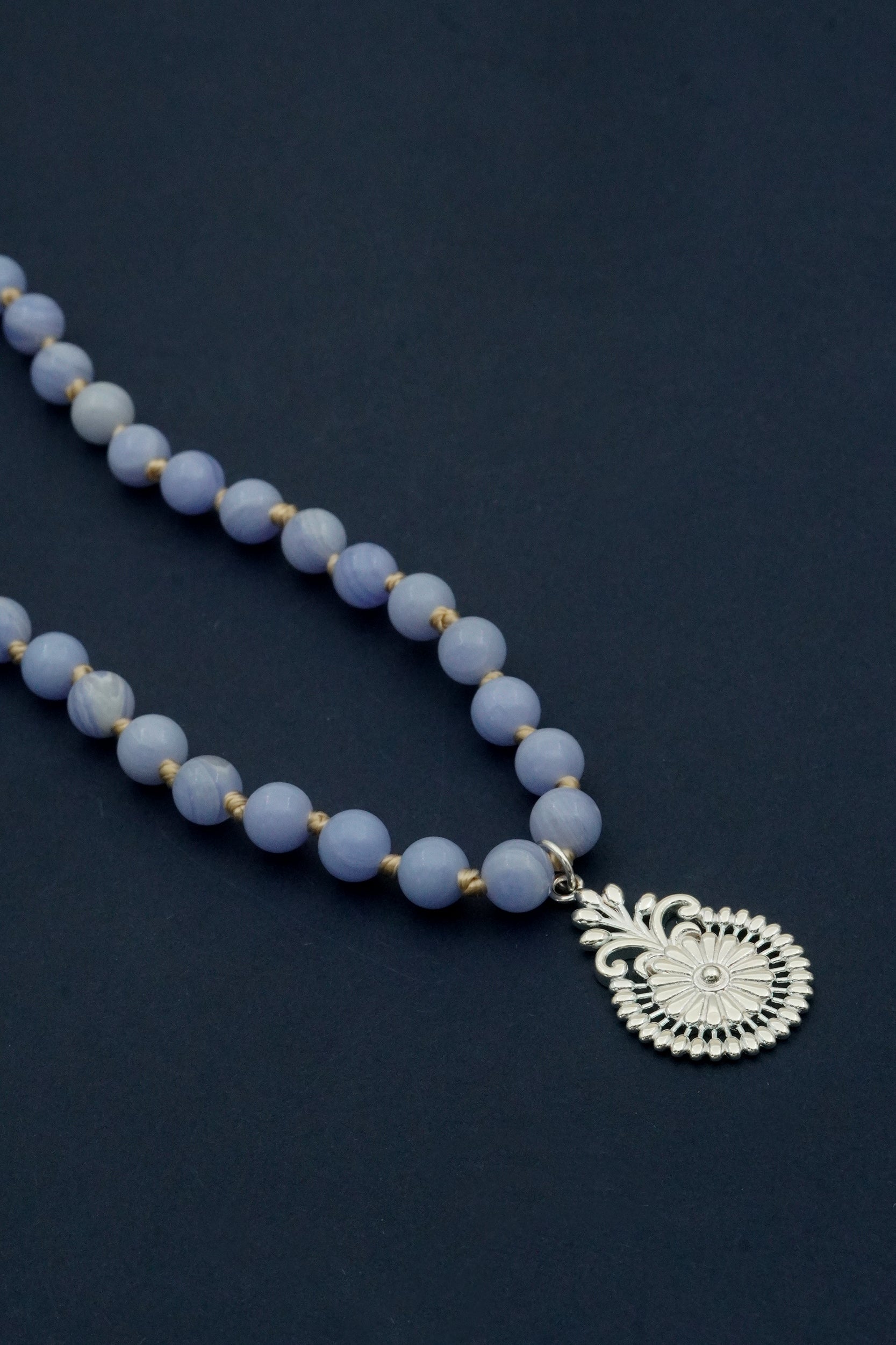 Blue lace agate beaded prayer necklace with a silver pendant on a dark background