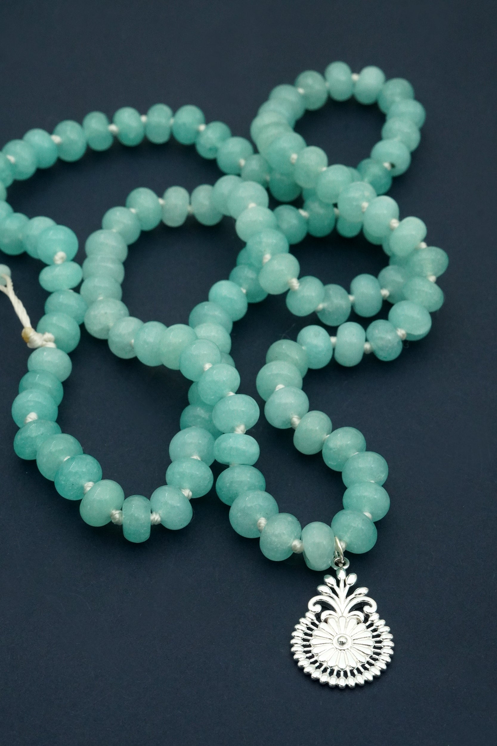Turquoise crystal beaded necklace with a silver pendant on a dark background