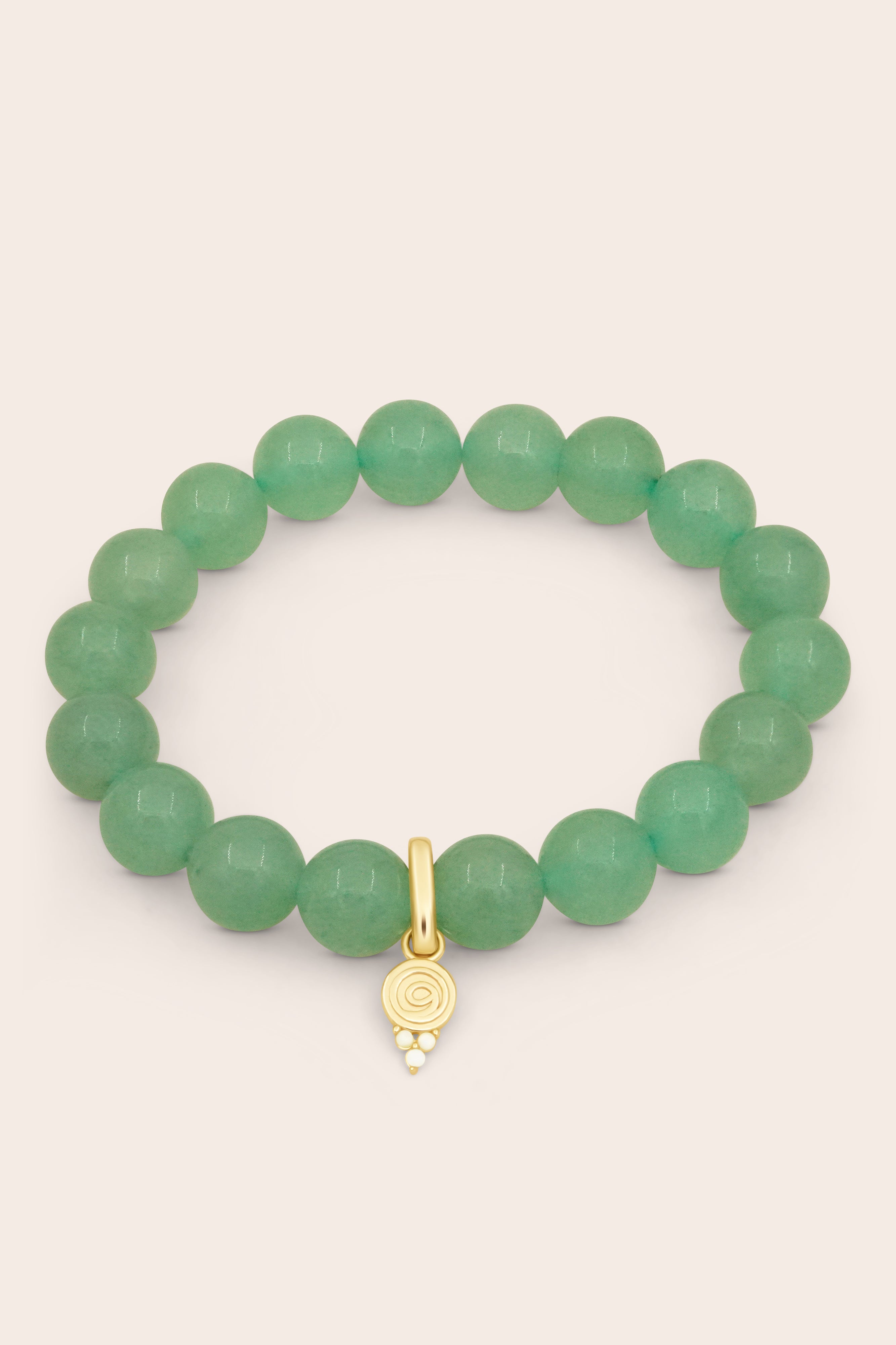 Green aventurine crystal beaded bracelet with a gold gratitude charm on a beige background