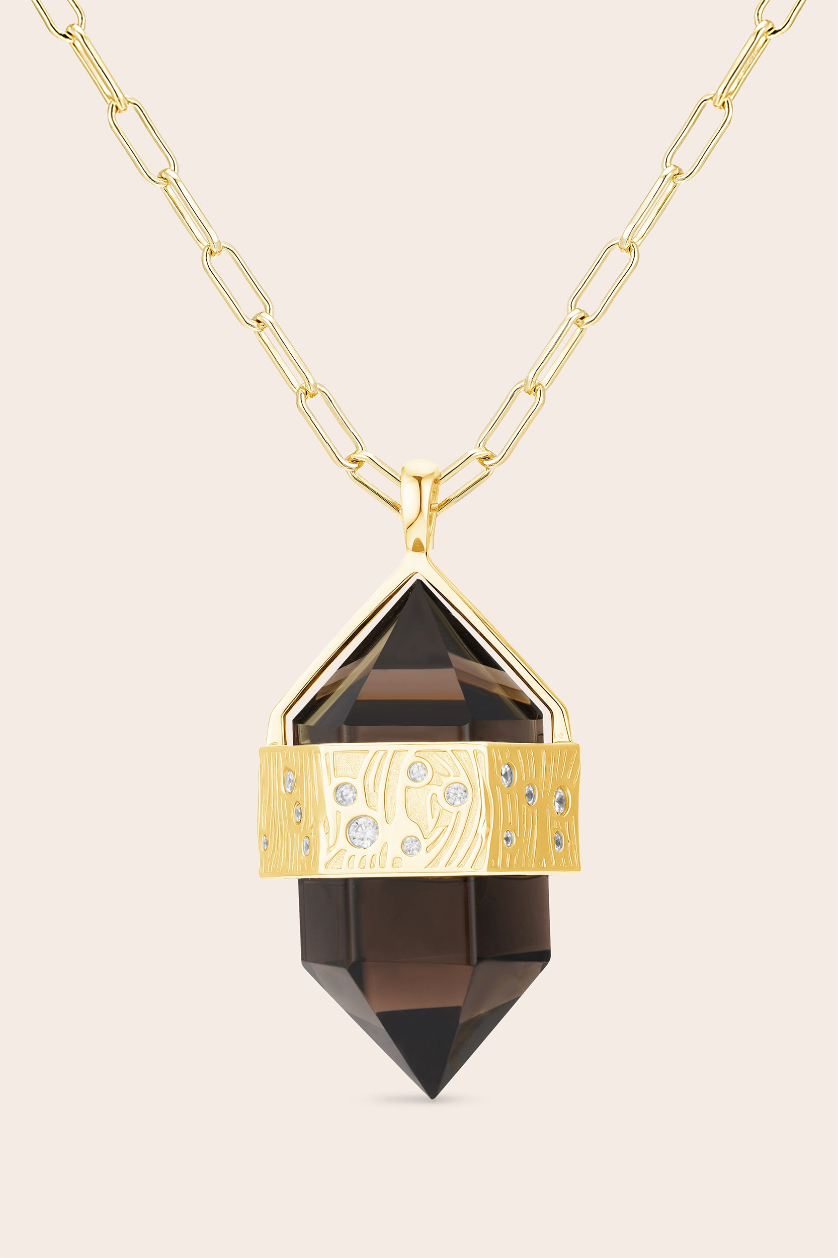 Gold necklace with a smoky crystal pendant on a beige background