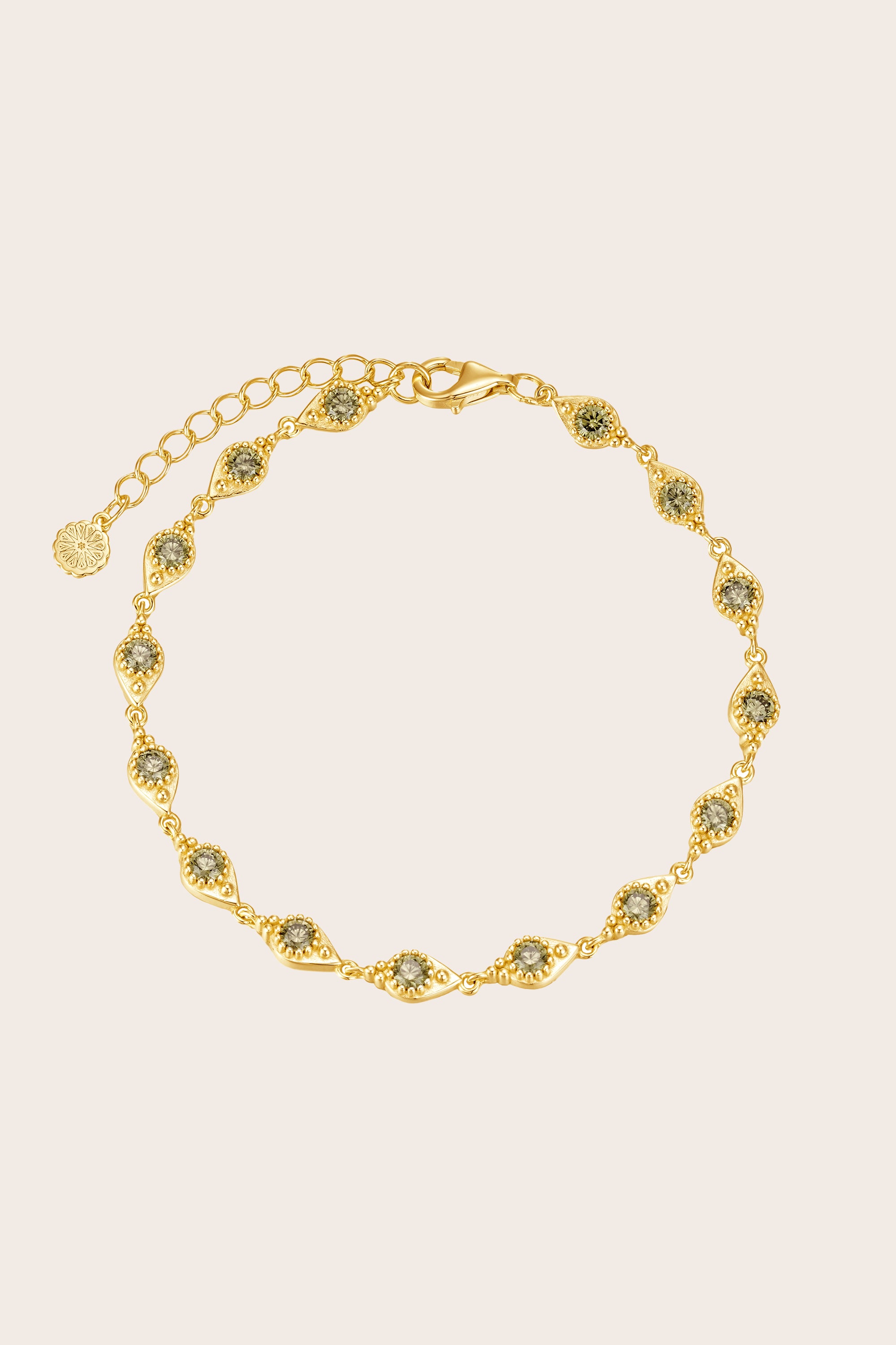 Gold bracelet with green gemstones on a beige background