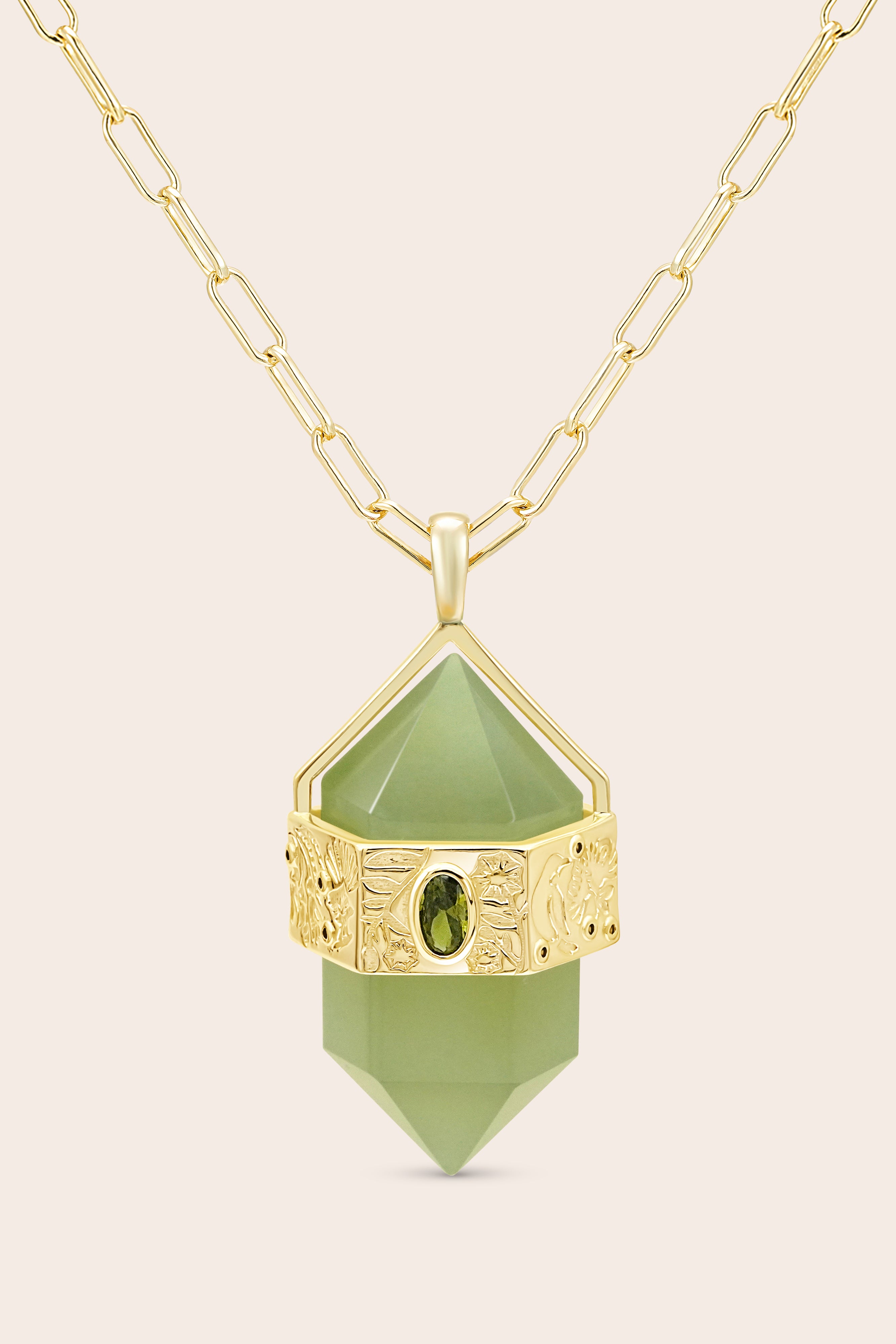 Gold necklace with a green pendant on a beige background