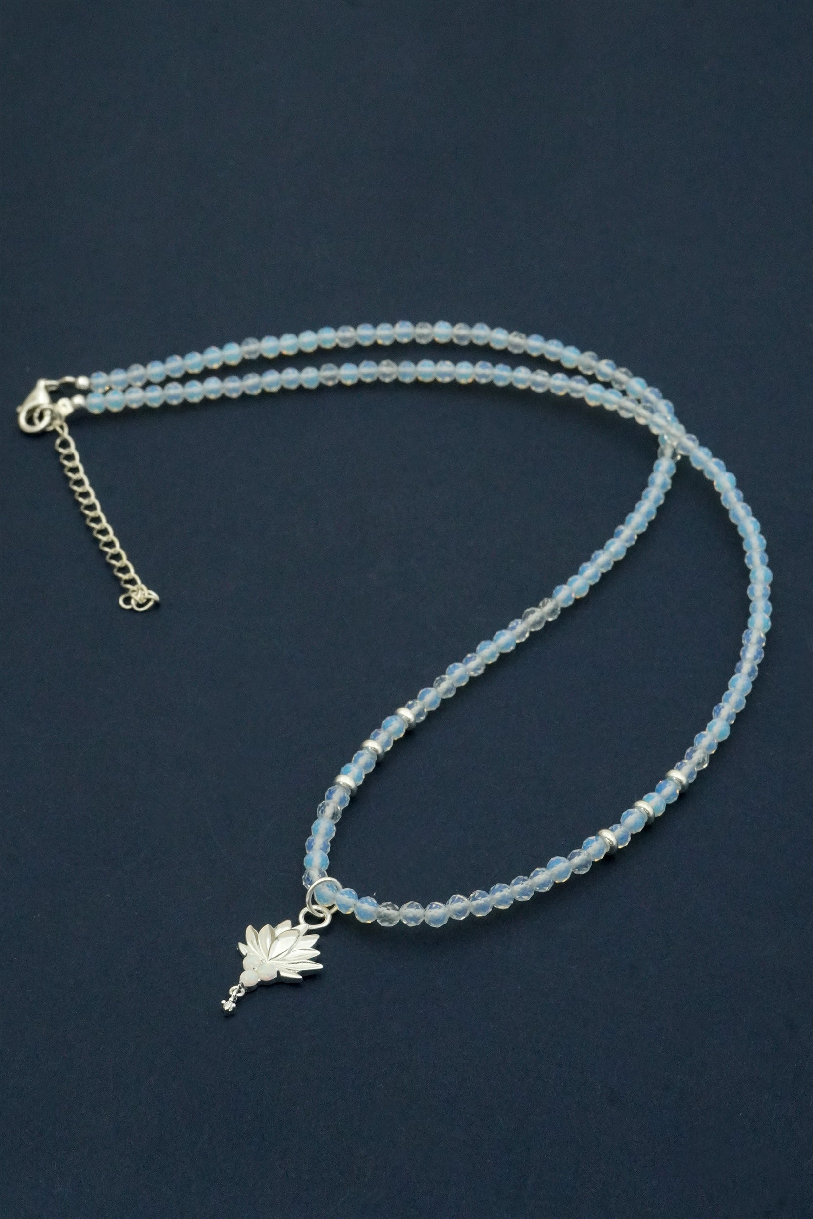 Blue beaded necklace with a silver charm on a dark blue background