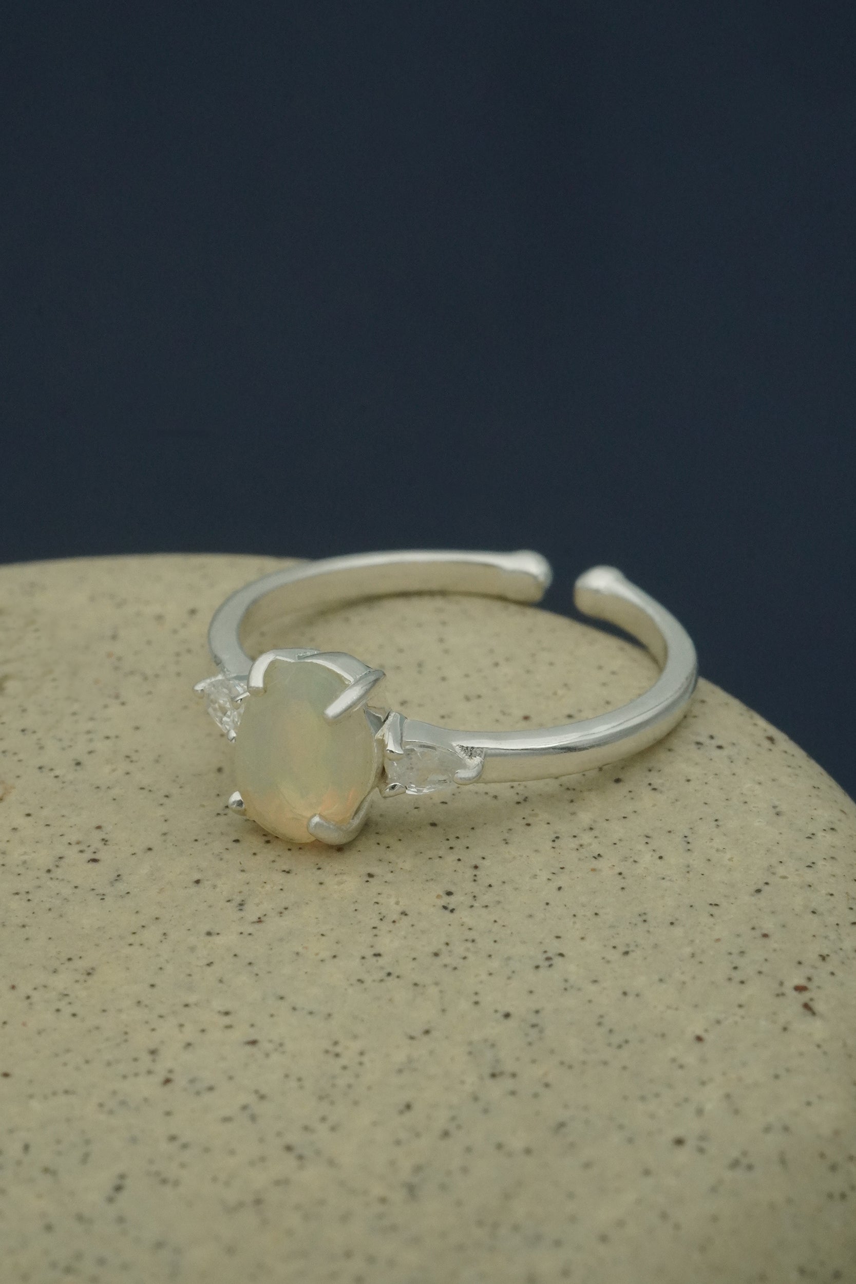 Silver ring with a central opal gemstone on a textured surface