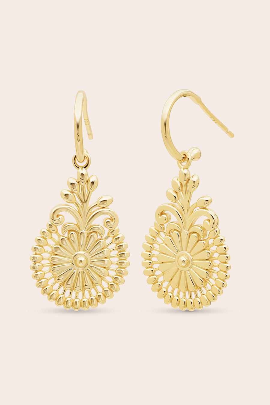 Gold filigree statement earrings on a beige background