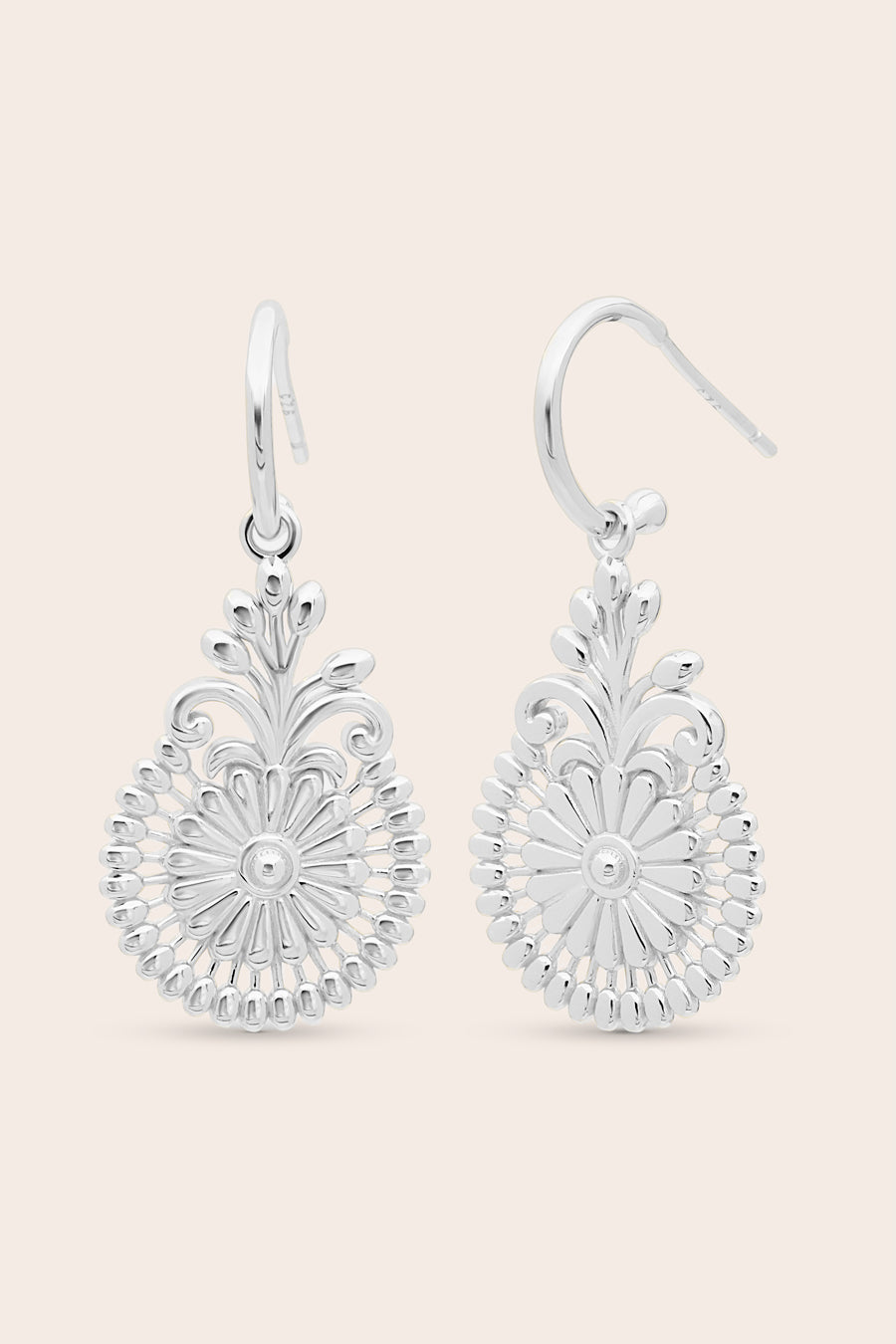 Pair of silver floral earrings on a light pink background