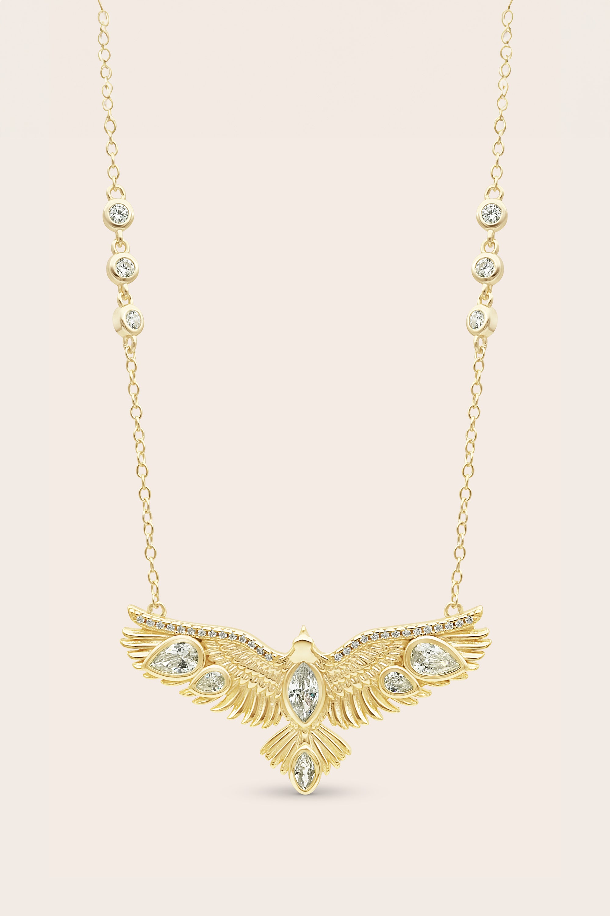 Gold necklace with an eagle-shaped pendant on a beige background