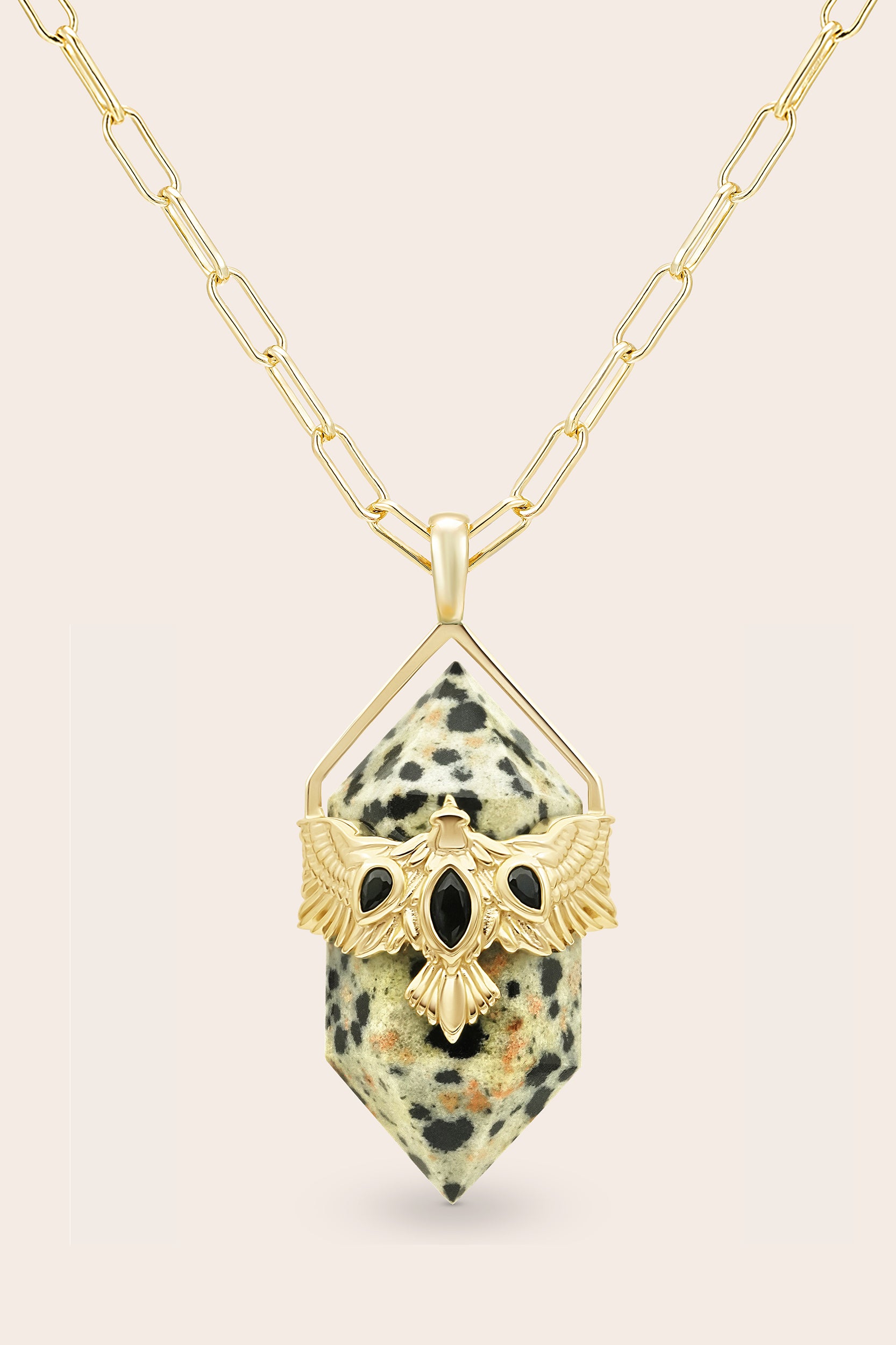Necklace with a gold pendant featuring a natural Dalmatian jasper crustal on a beige background