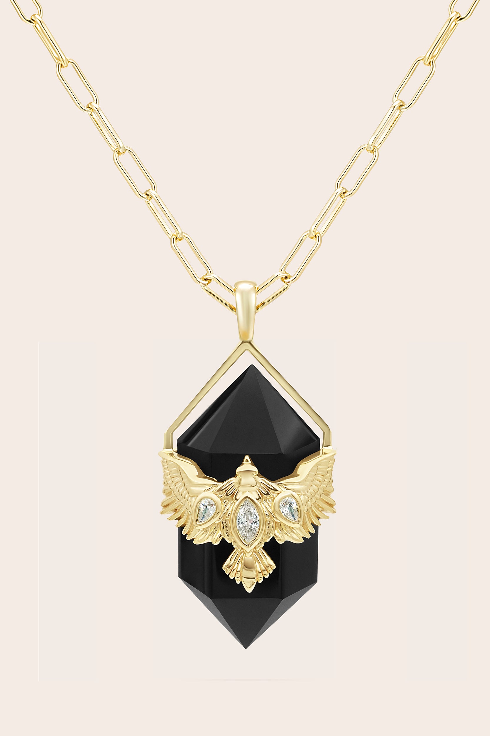 Gold nz bird necklace with a black agate pendant on a beige background