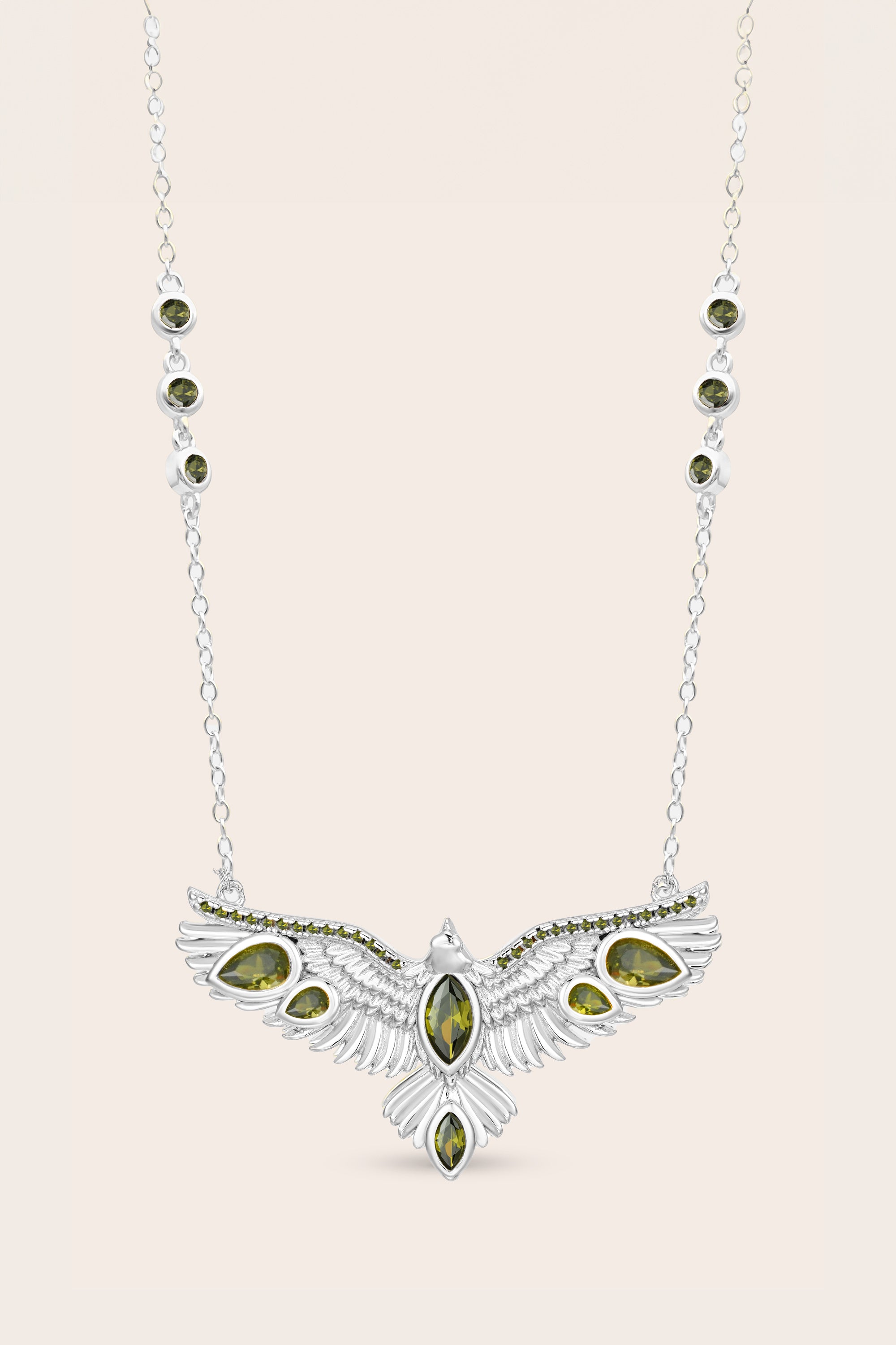 Silver hawk necklace with green gemstone pendant on a light pink background