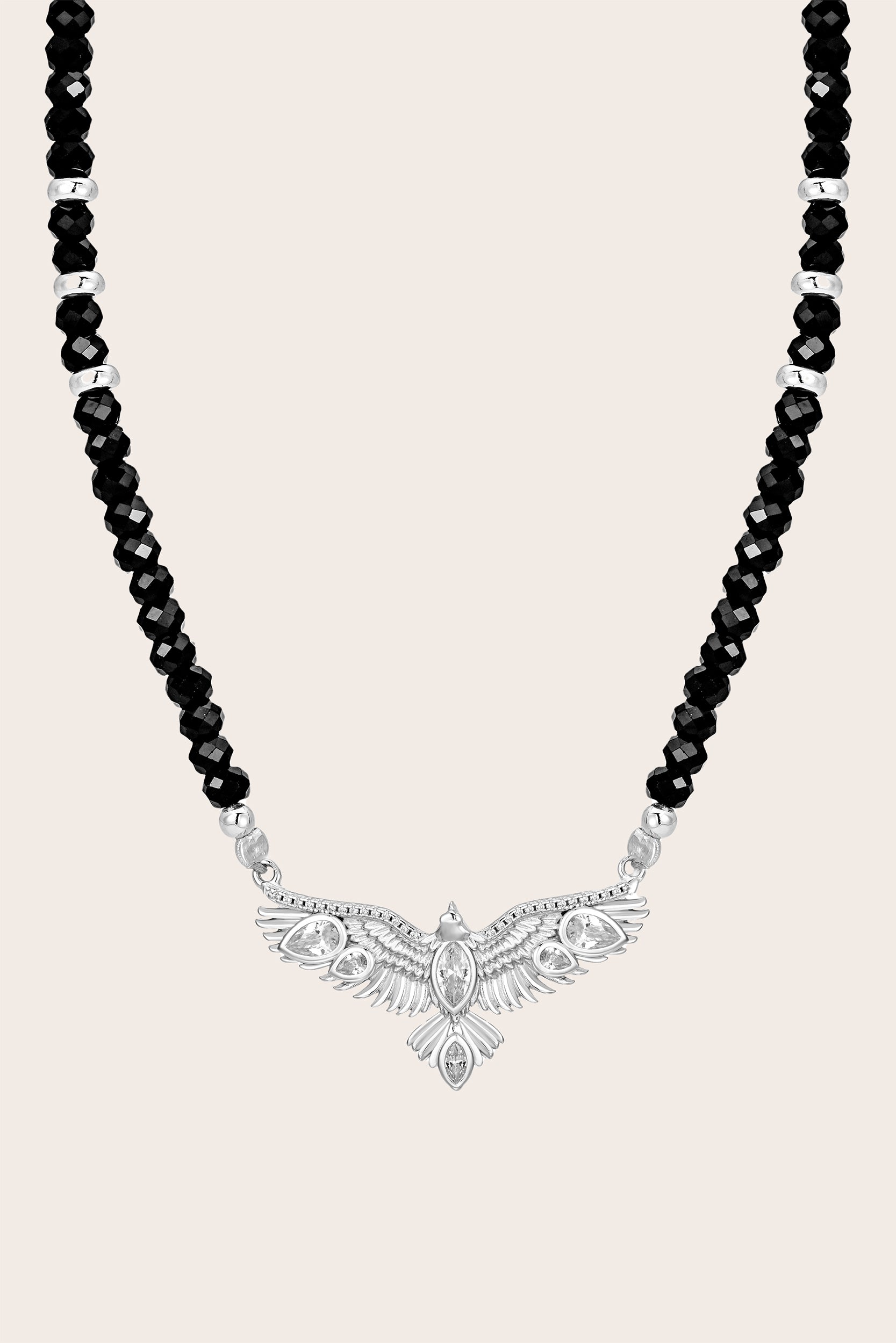 Necklace with black beads and a silver hawk pendant on a light pink background