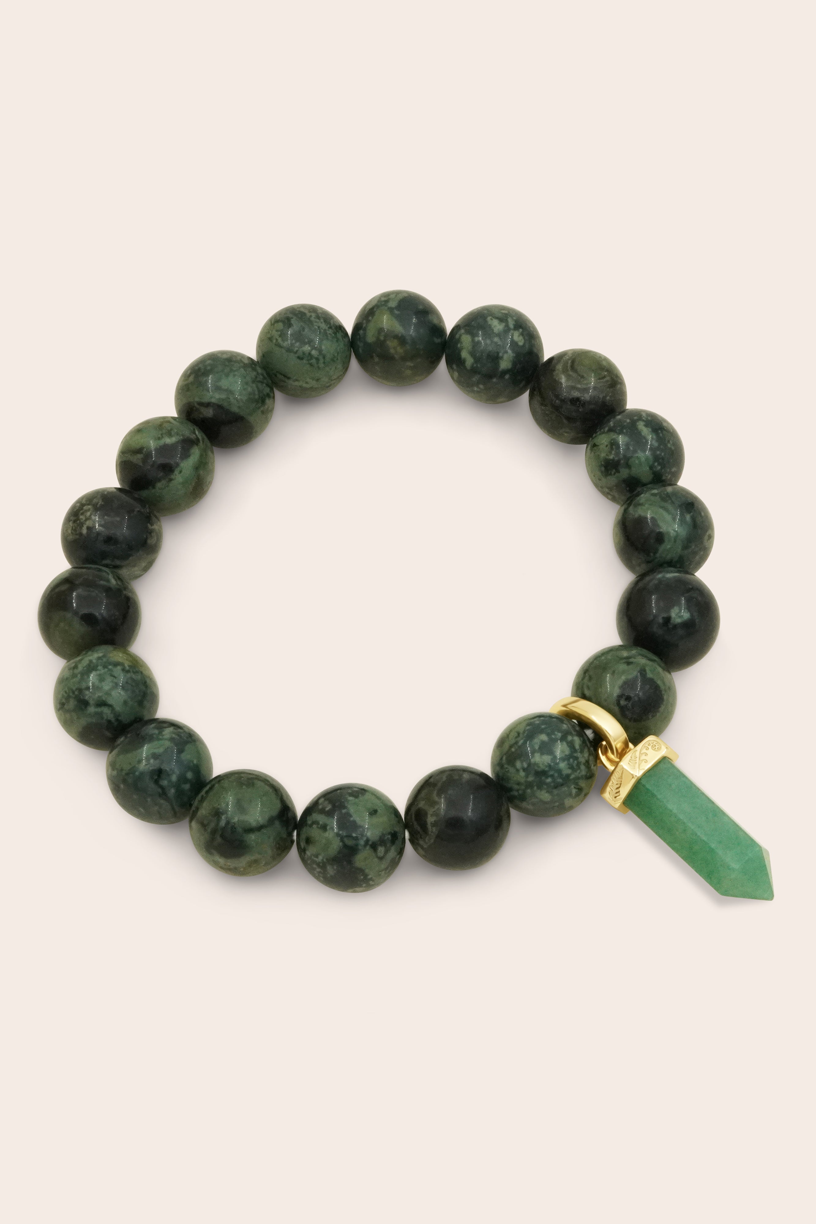 Green jasper crystal beaded bracelet with a gold and green strength charm on a beige background