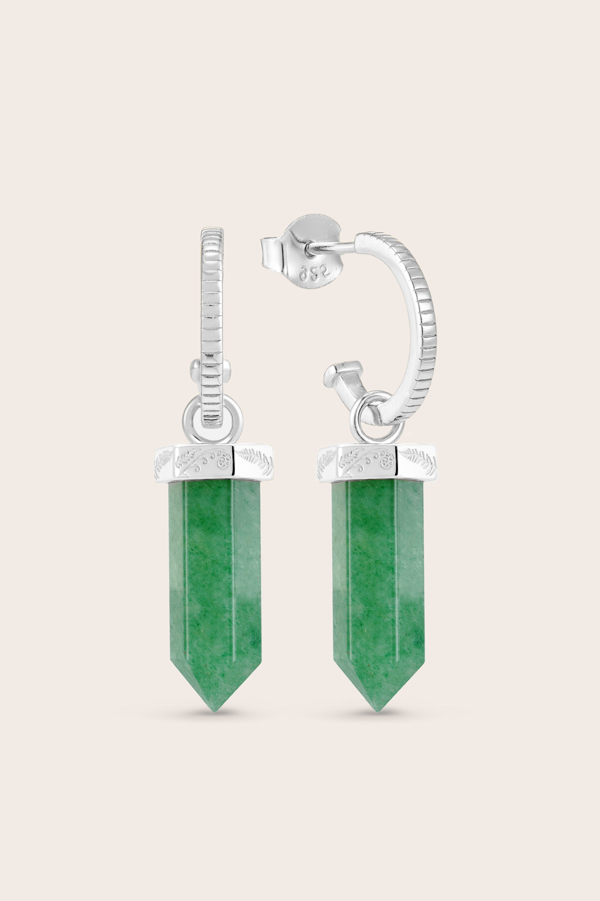 Green crystal earrings with silver hoops on a beige background