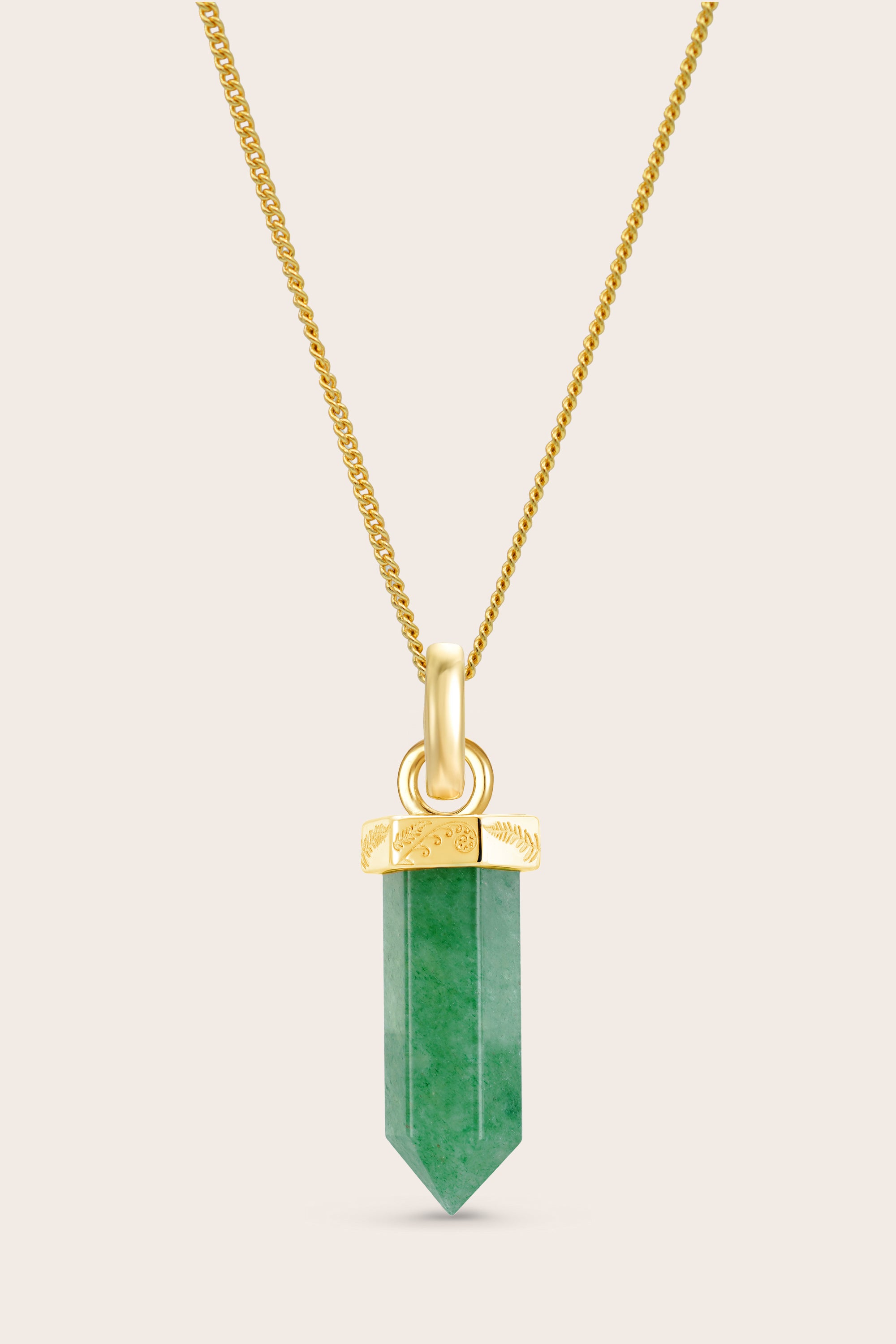 Gold necklace with a green aventurine crystal pendant on a beige background