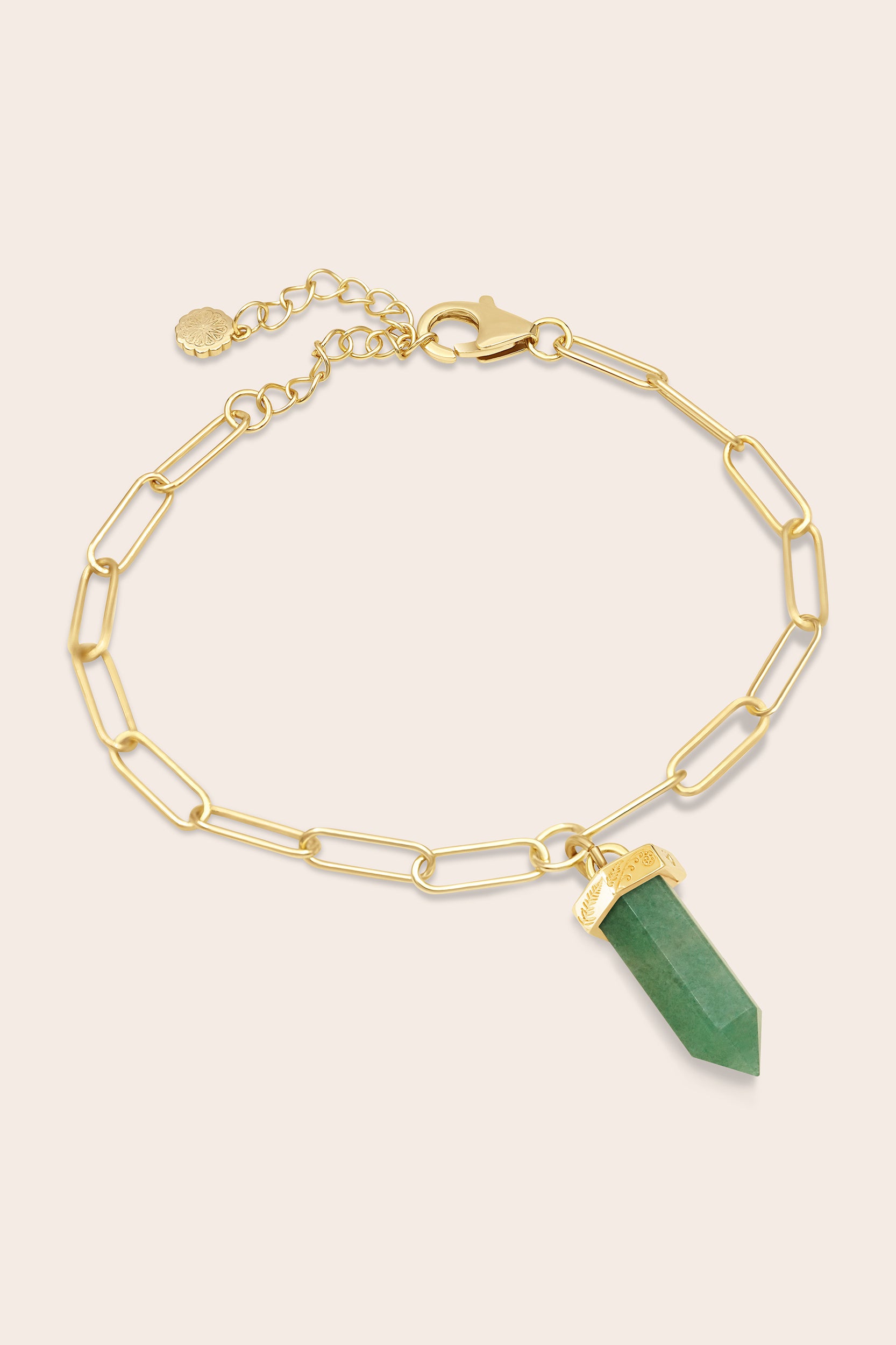 Gold paperclip chain bracelet with a green aventurine crystal pendant on a beige background