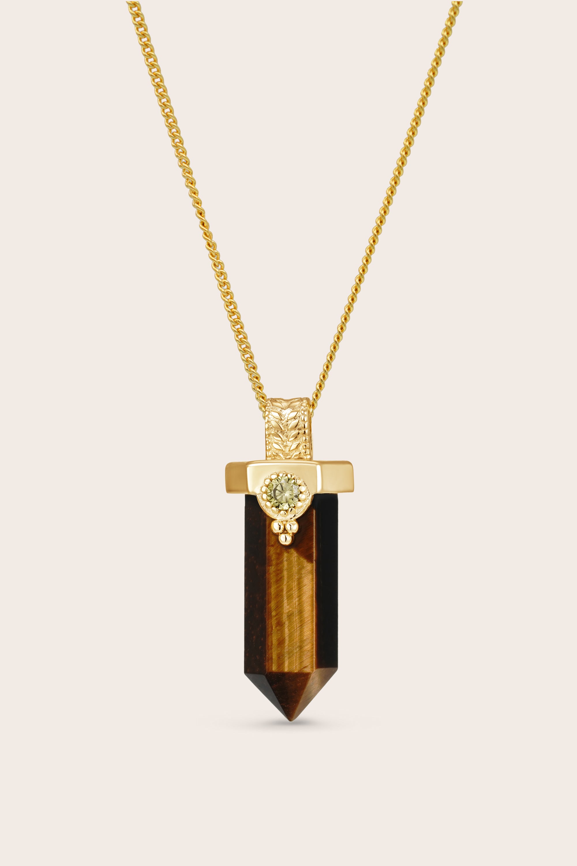 Necklace with a gold chain and tiger's eye pendant on a beige background