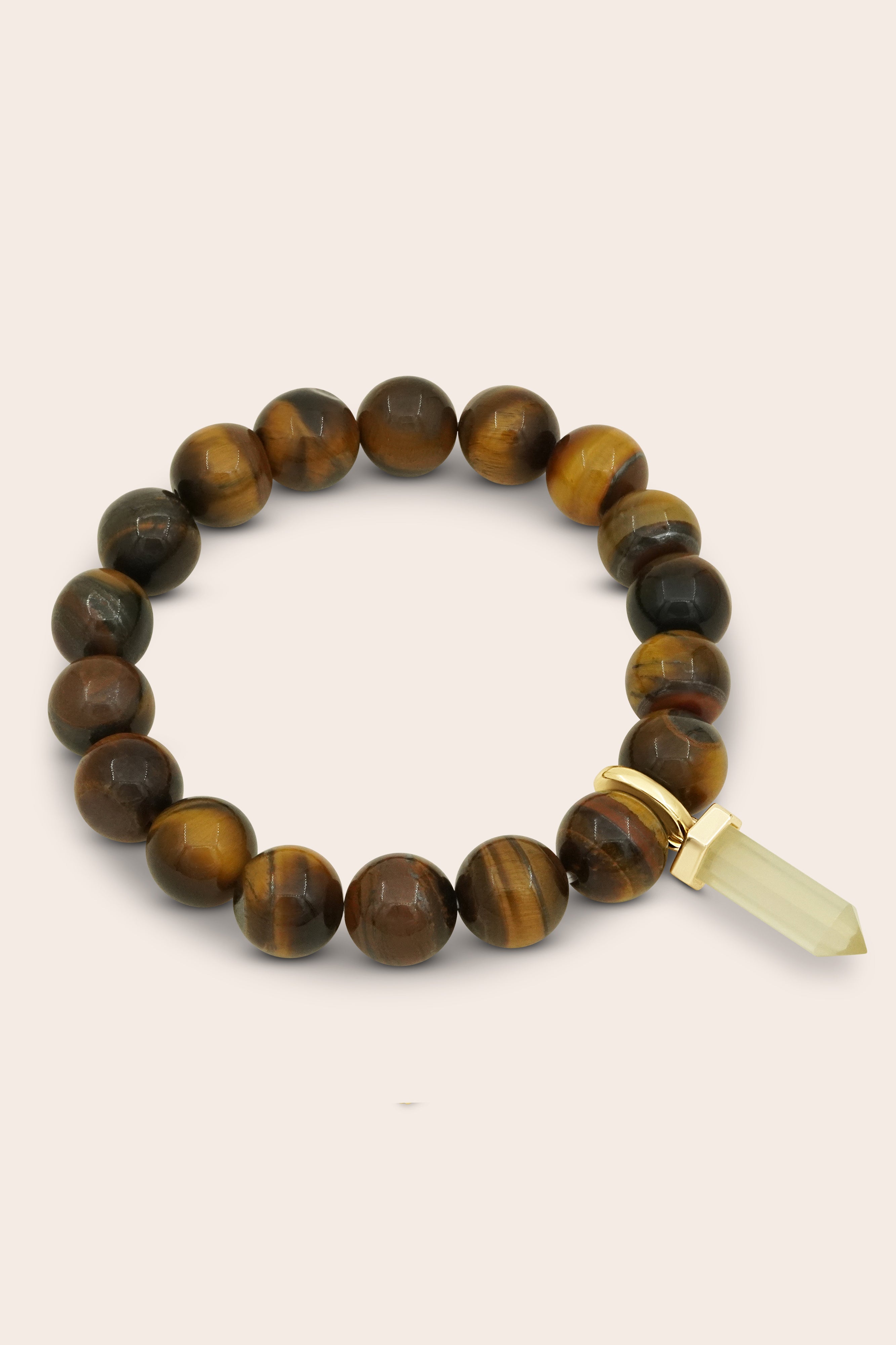 Tigers eye crystal beaded bracelet with a gold citrine charm on a beige background