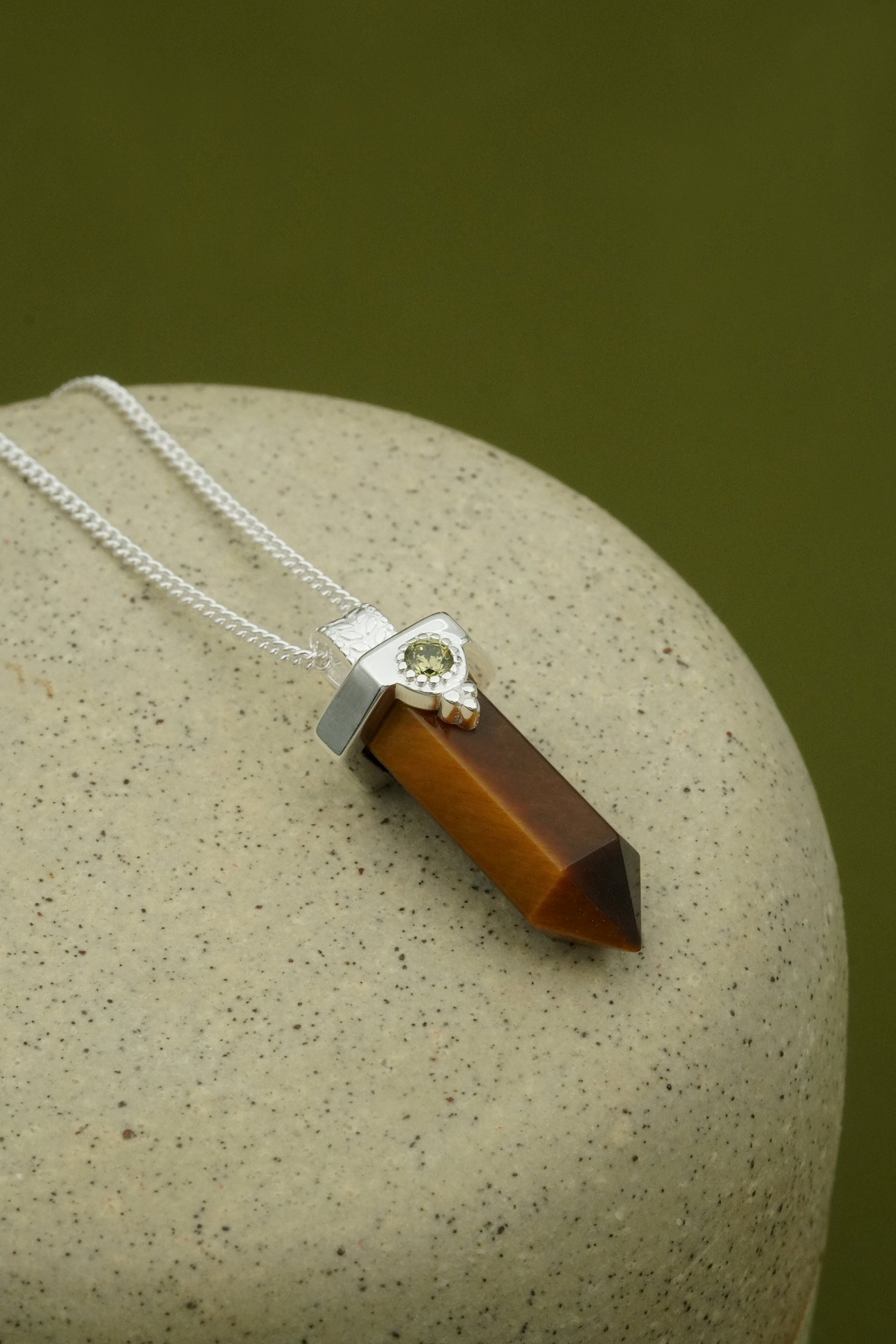 Necklace with a brown tiger's eye pendant on a stone surface