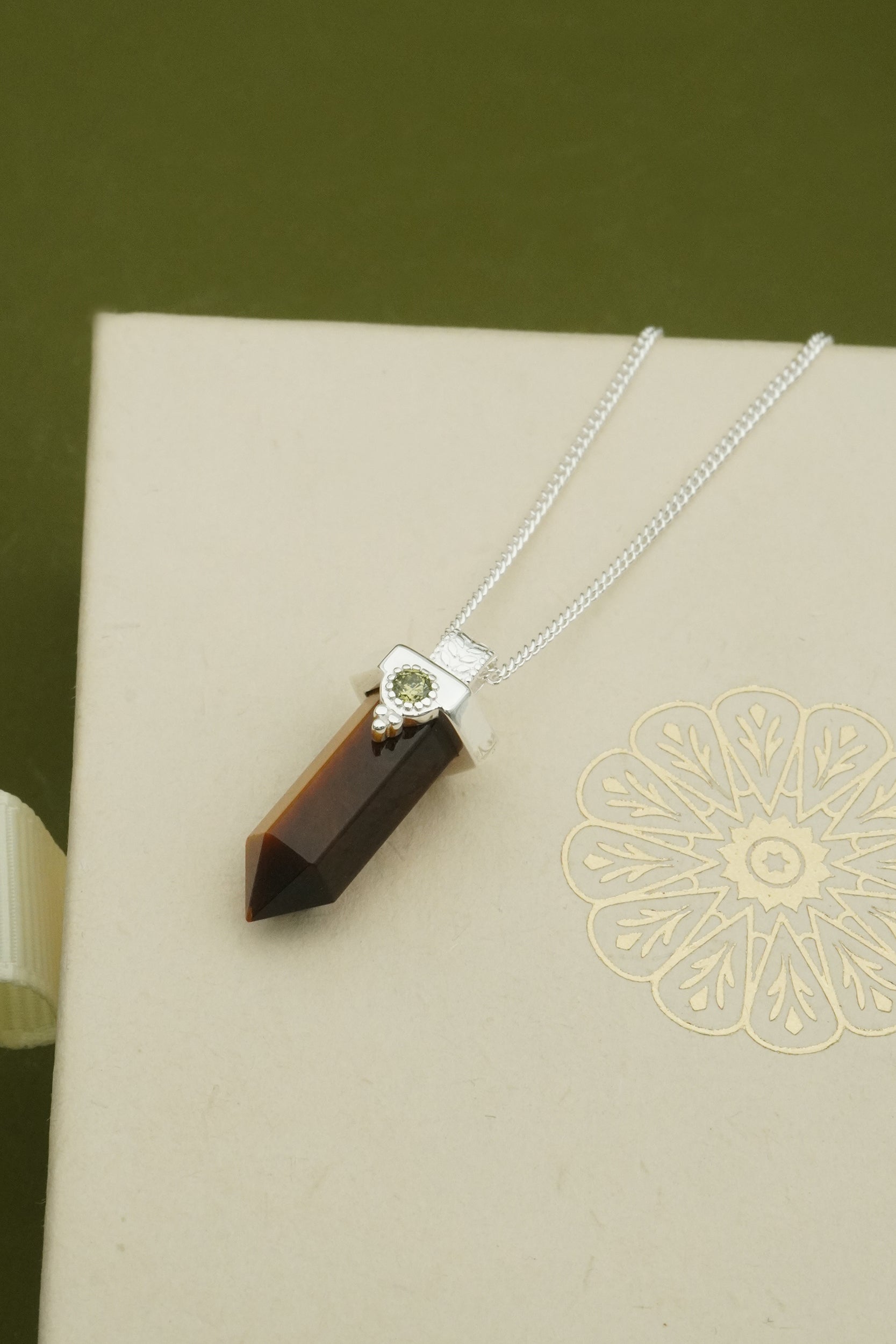 Necklace with a brown tigers eye pendant on a decorative box