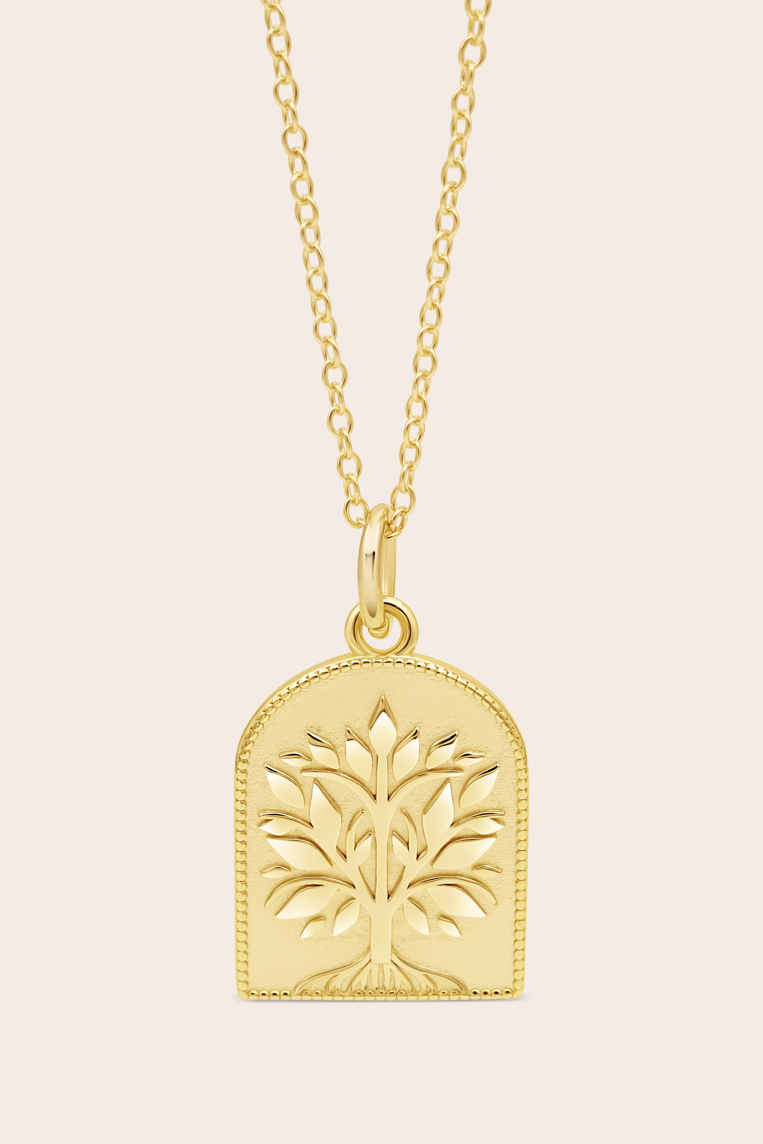 Gold tree of life necklace on a beige background