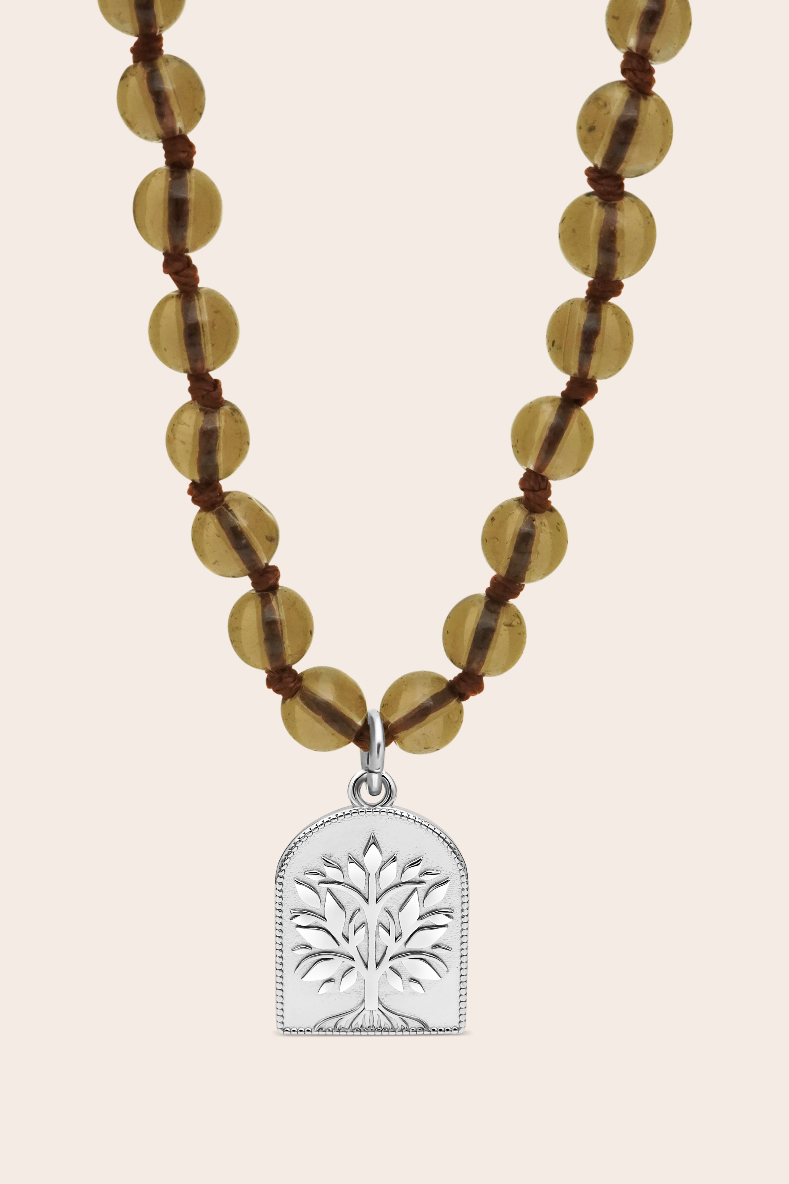 Brown Smoky Quartz Mala Necklace with brown beads and a silver tree pendant on a beige background
