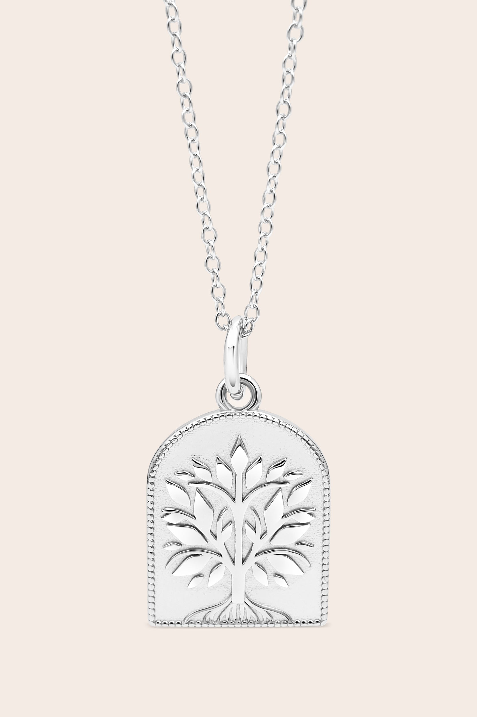 Silver necklace with a tree-of-life pendant on a light pink background