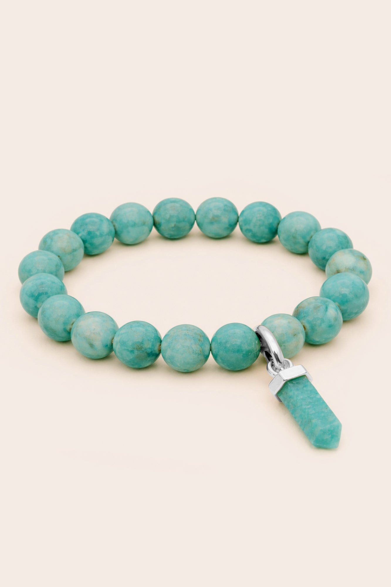 Amazonite beaded bracelet with a silver clasp and charm on a beige background