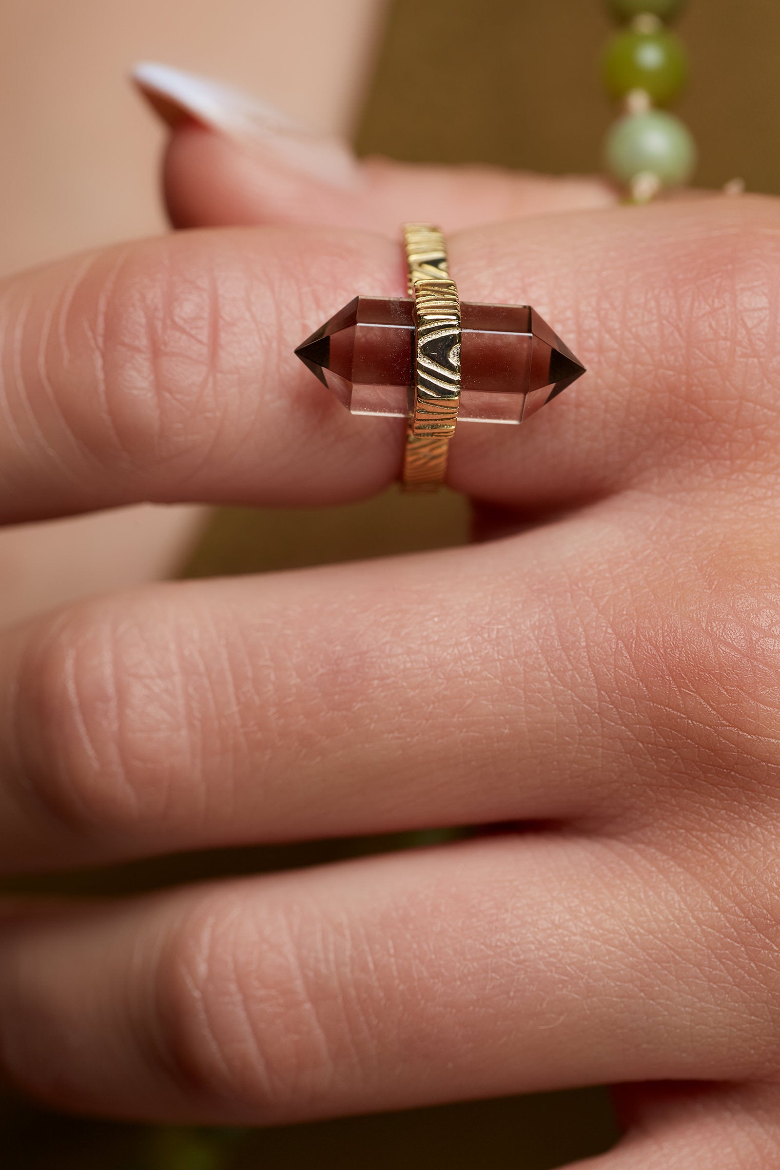 Close-up of a hand wearing a ring with a brown gemstone and gold band.