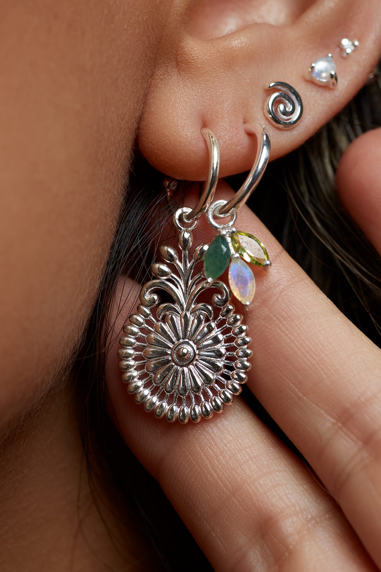 Close-up of a person wearing a silver earring with a flower design.