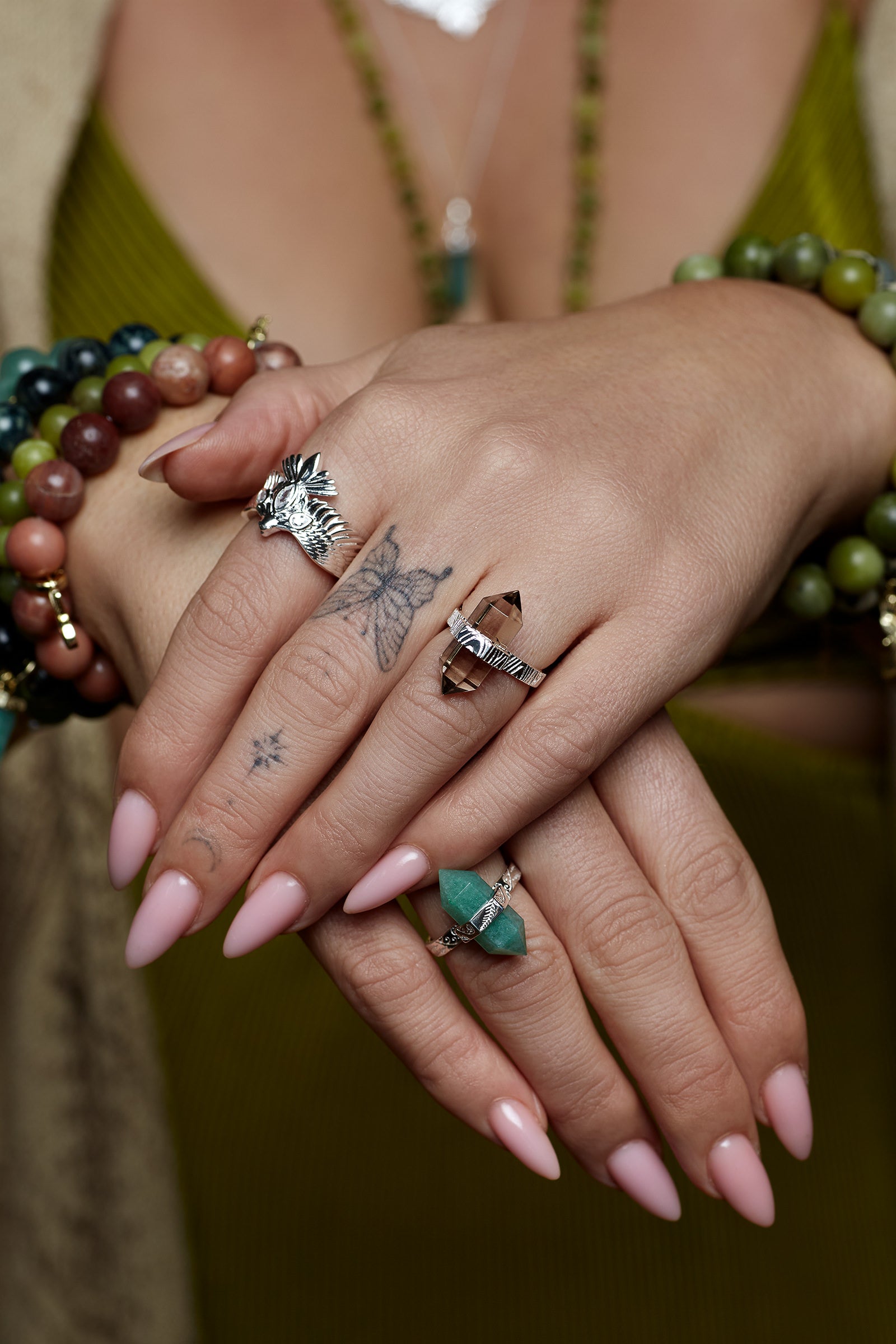 Close-up of hands with multiple layered rings and bracelets on a blurred background