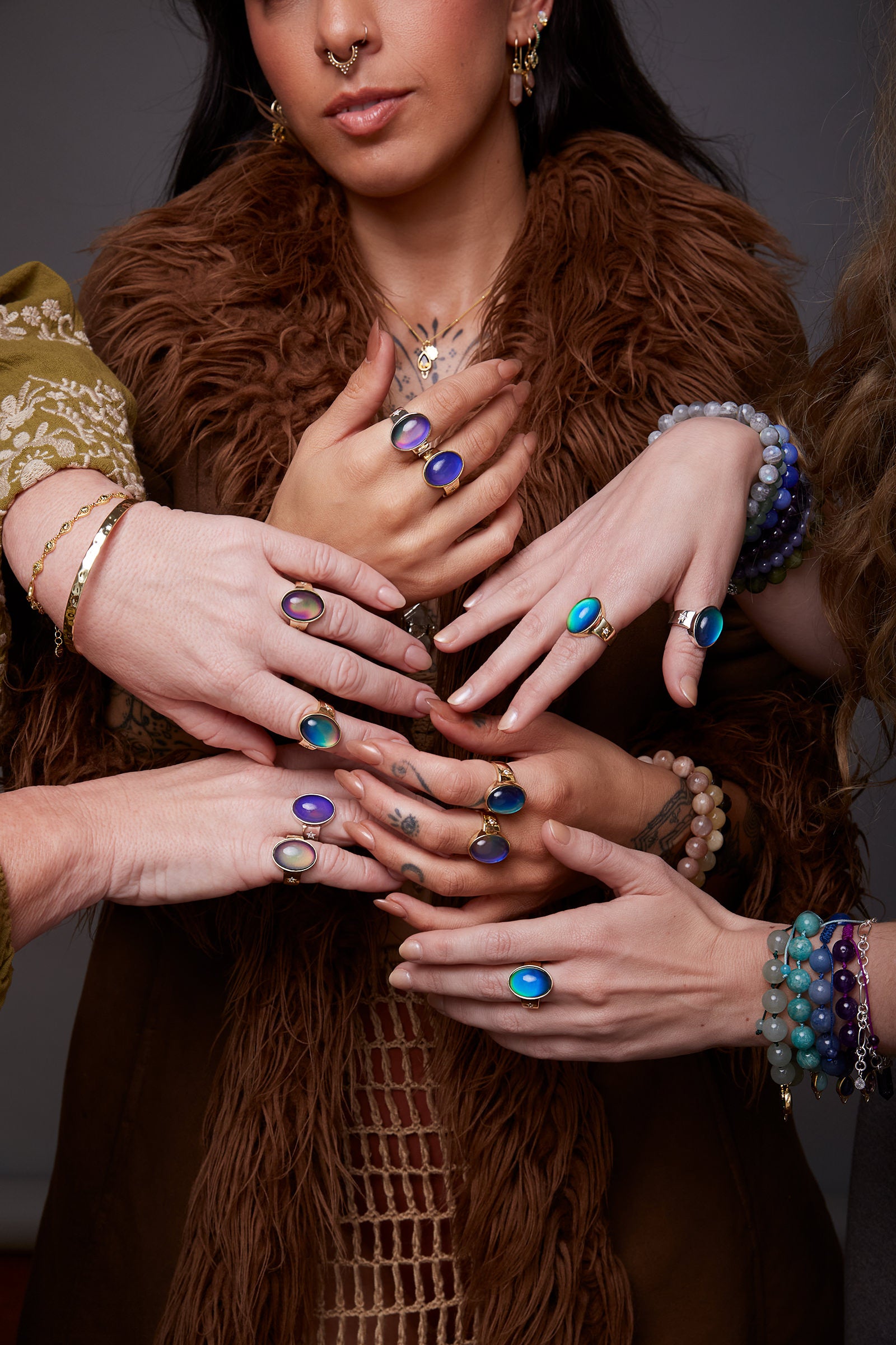 Close-up of multiple hands with colourful mood rings