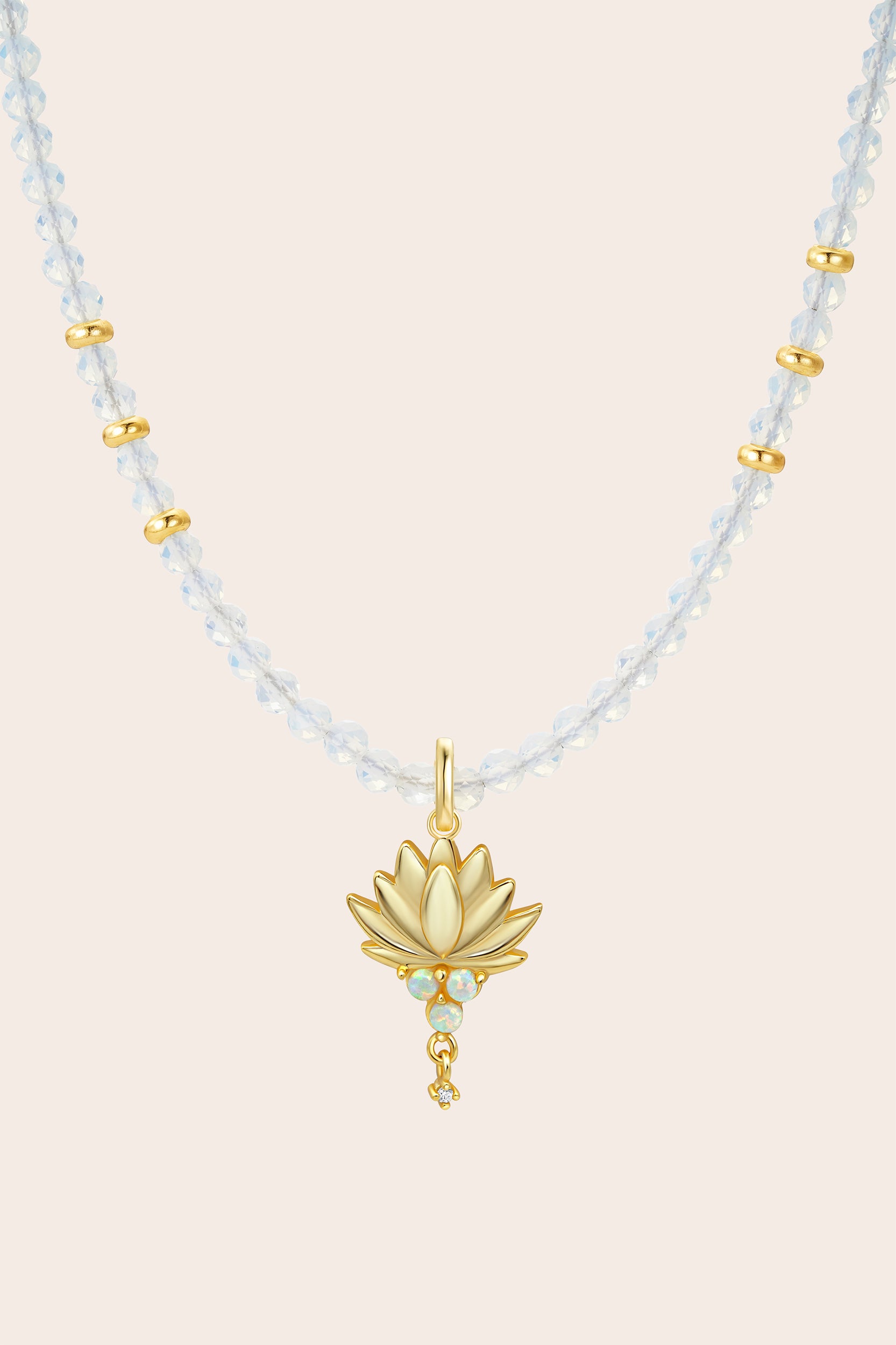 Necklace with gold lotus pendant and light blue beads on a beige background