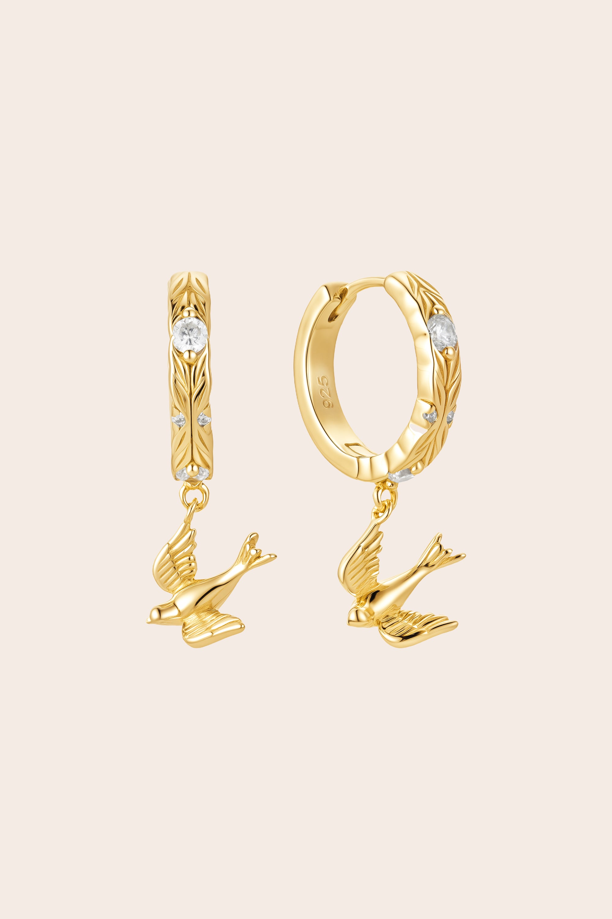 Gold hoop earrings with bird designs on a beige background