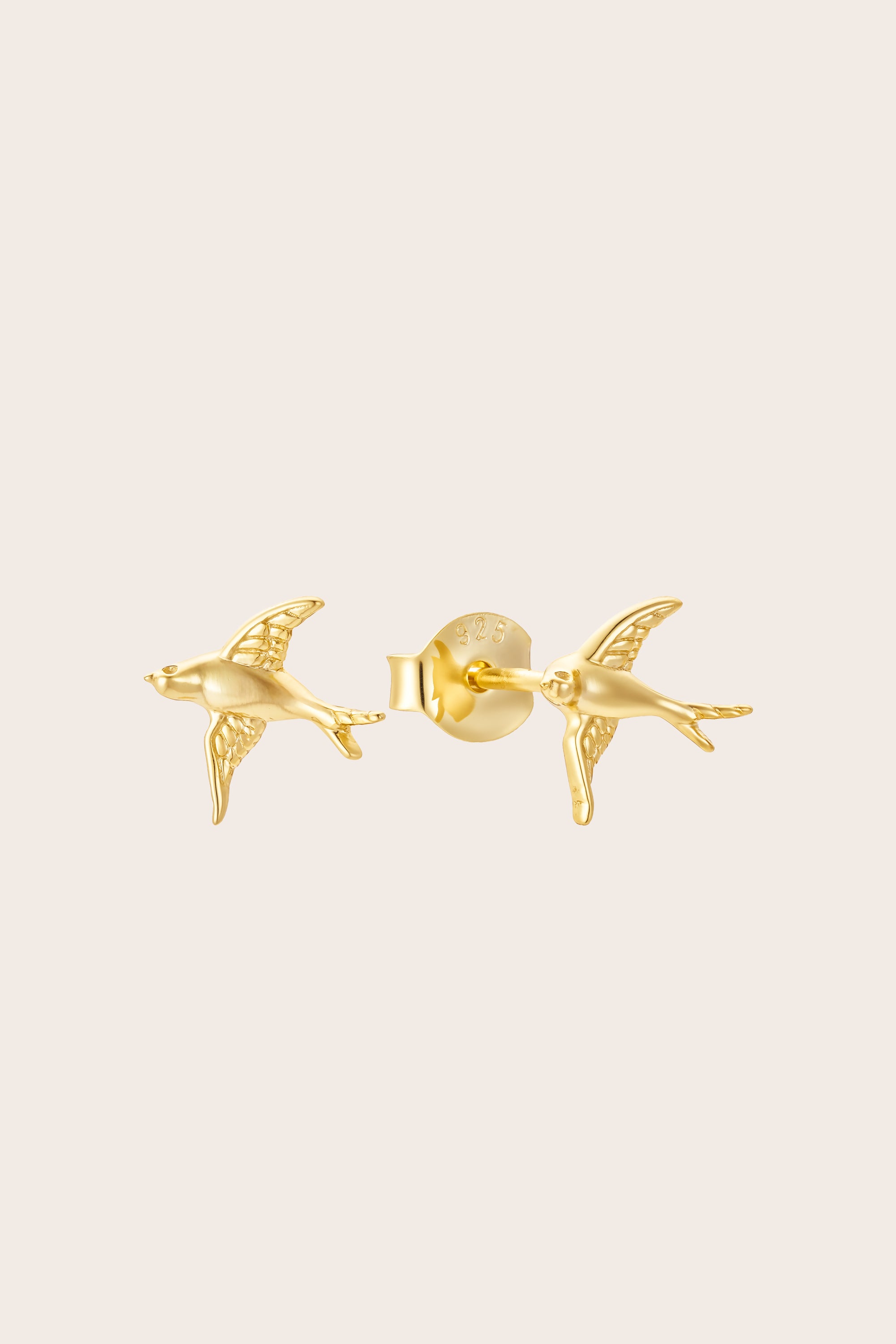 Gold bird-shaped earrings on a beige background