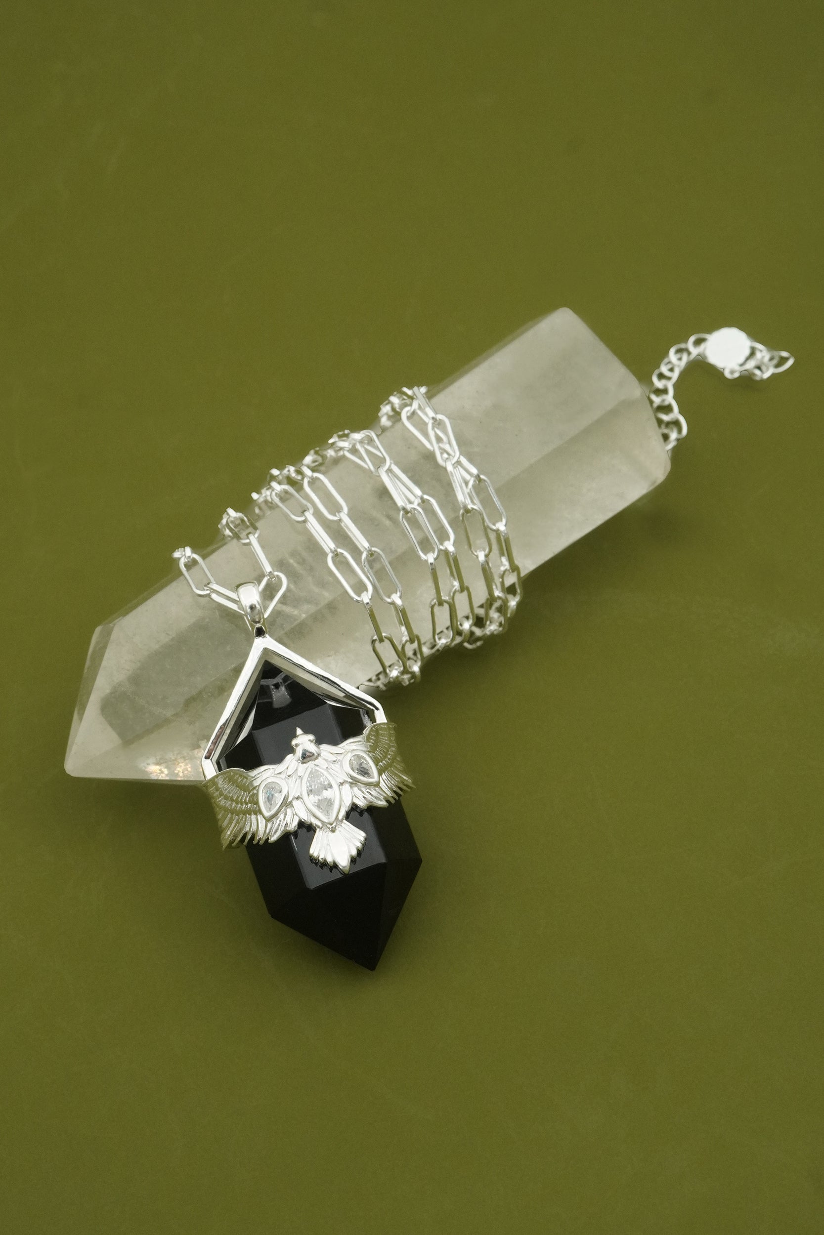 Silver necklace with black obsidian gemstone with soaring NZ hawk bird on a green background