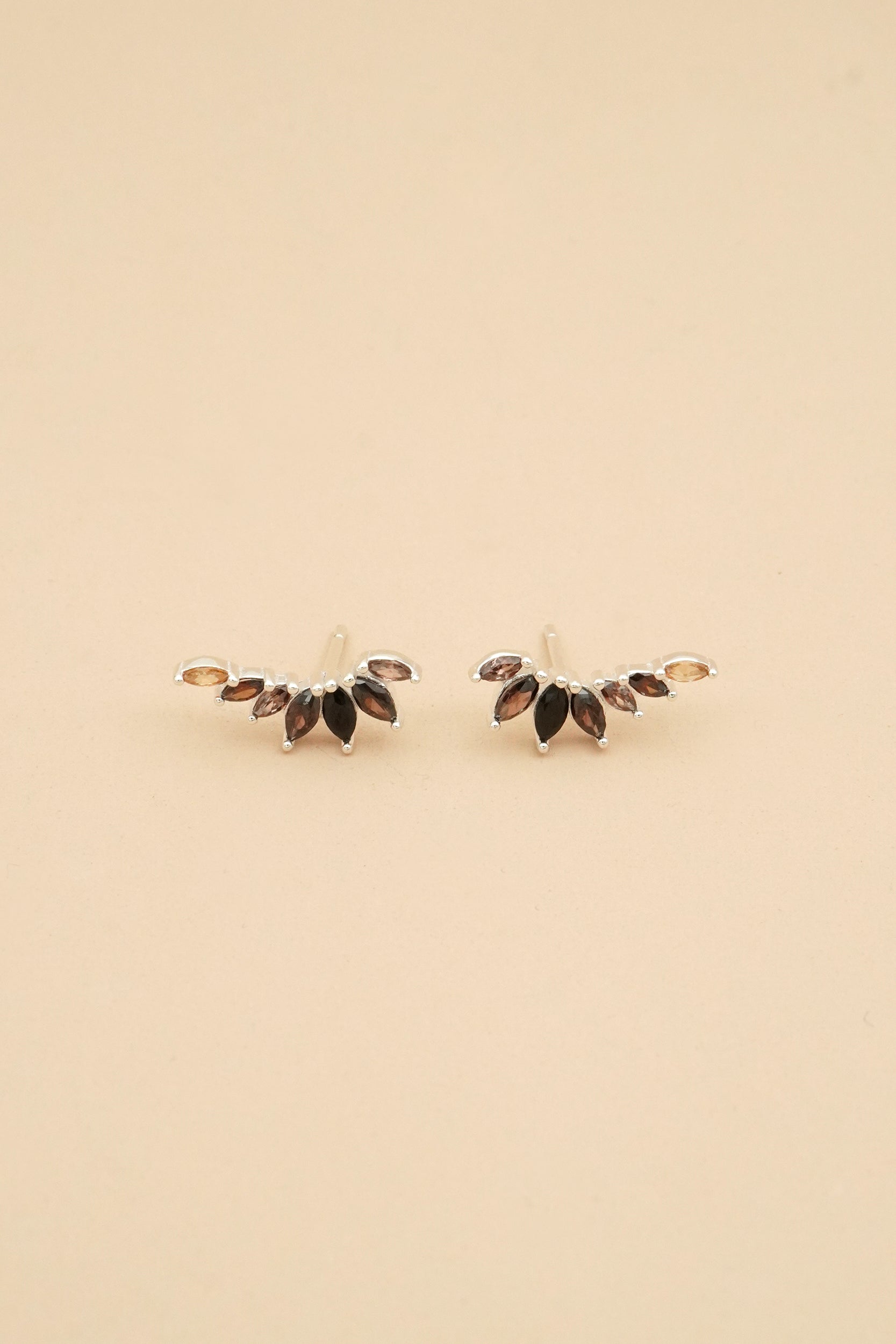 Pair of earrings with marquise-shaped gemstones on a beige background